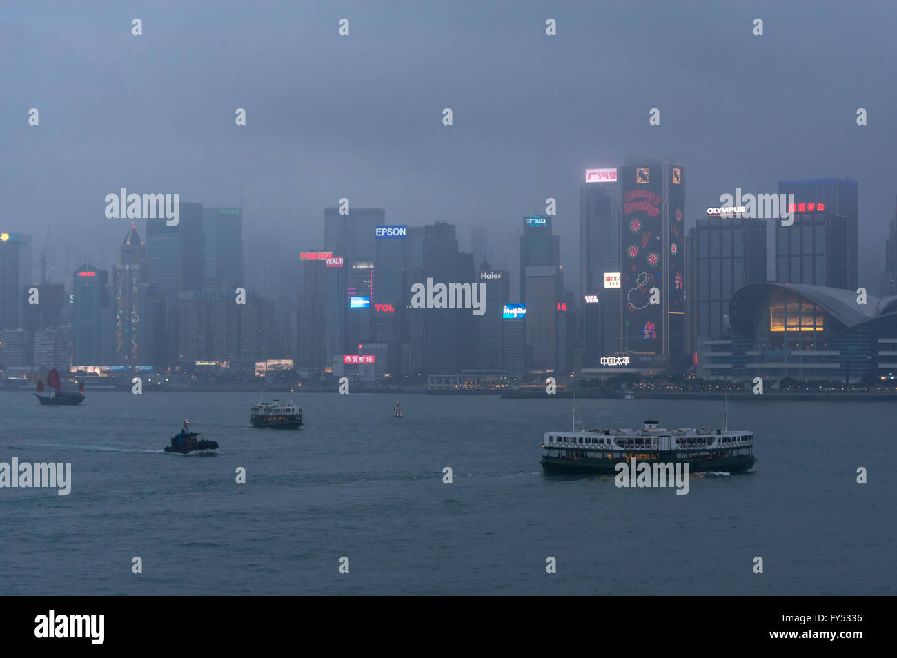 Star Ferries et autres bateaux traversant le Port Victoria de brouillard entre l'île de Hong Kong et de Kowloon au crépuscule du soir. Banque D'Images