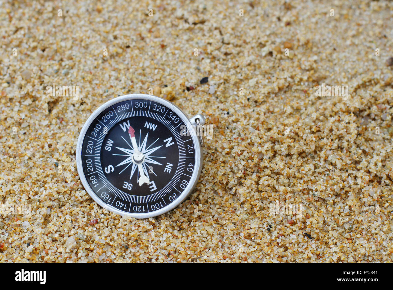 Une vieille boussole style orienté à l'ouest reposant sur une plage de sable. Banque D'Images
