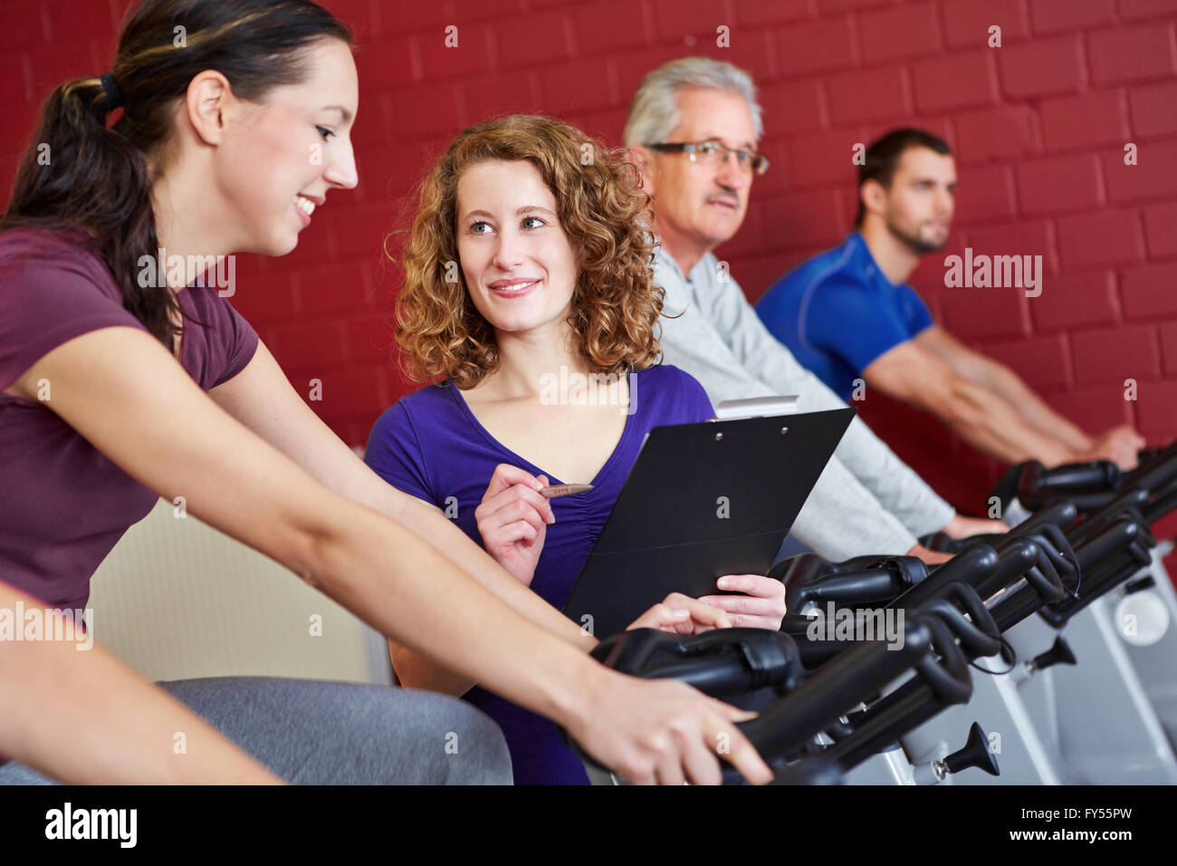 Femme fitness trainer helping woman sur spinning bike en centre de remise en forme Banque D'Images
