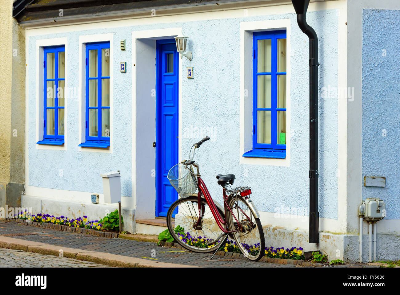 Trelleborg, Suède - 12 Avril 2016 : Vélo stationné à l'extérieur un pastel peint en bleu et blanc maison d'habitation. Parterre avec pansi Banque D'Images