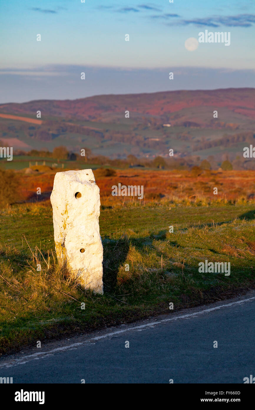 Une vue de la montagne Halkyn vers Moel-y-parc dans la gamme Clwydian hills sur le Flintshire de la cuisinière comme la lune se couche sur l'horizon et une ancienne route marker visible, la route en hiver Banque D'Images