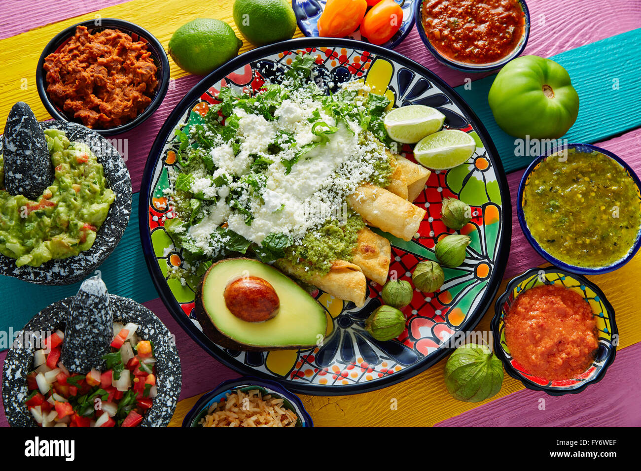 Cuisine mexicaine enchiladas vert avec guacamole et sauces sur tableau coloré Banque D'Images