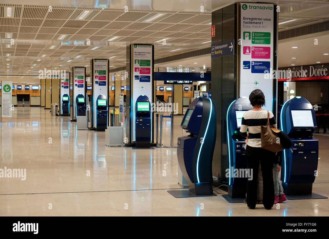 Passager utilisant l'enregistrement électronique dans la machine dans le hall de départ de l'aéroport de Paris Orly, Paris France Banque D'Images