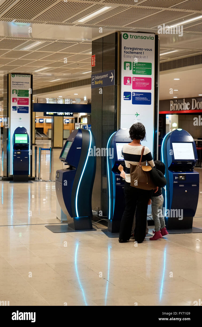 Passager utilisant l'enregistrement électronique dans la machine dans le hall de départ de l'aéroport de Paris Orly, Paris France Banque D'Images