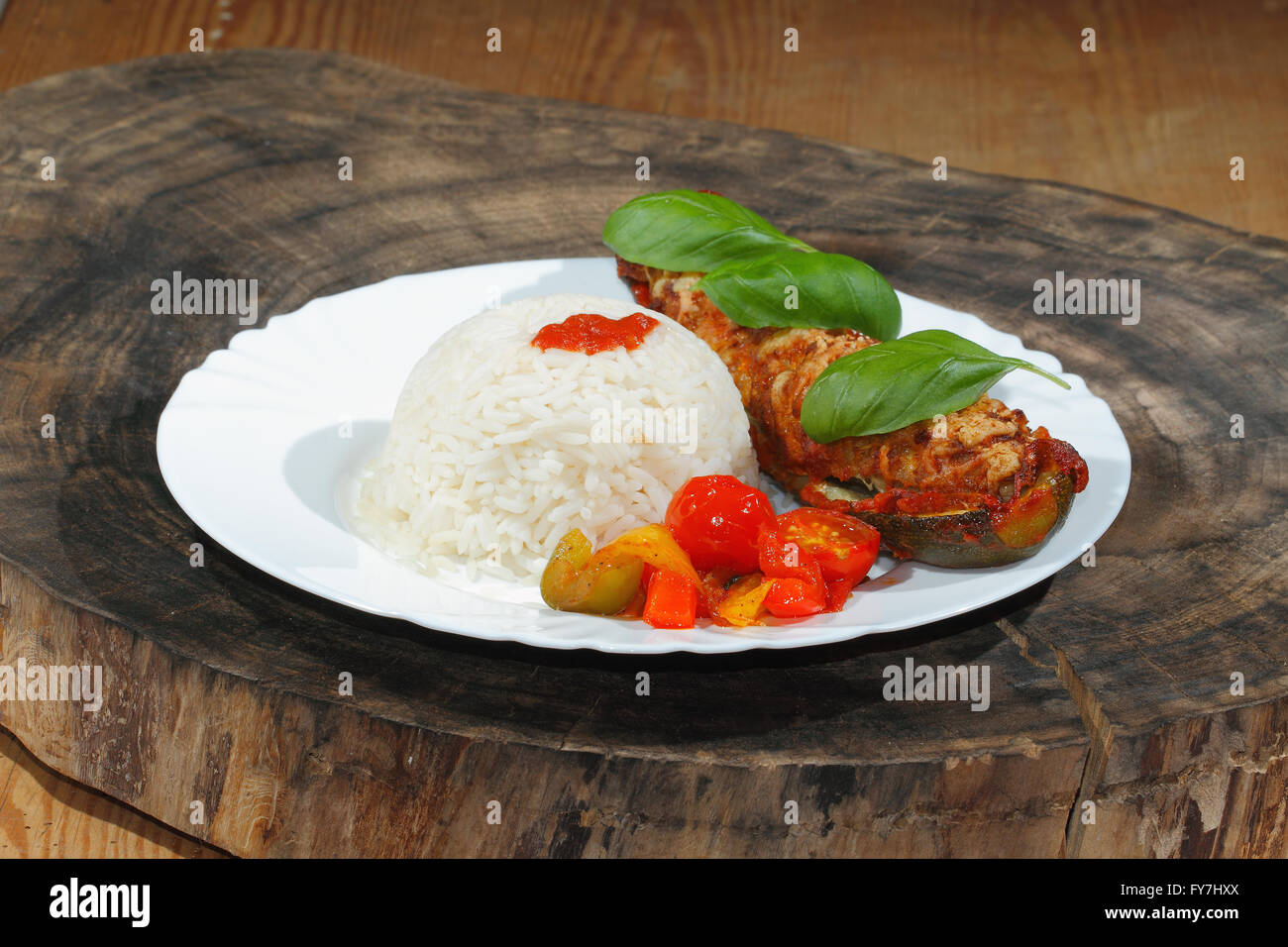 Courgette farcie, riz, compotée de poivrons et tomates, légumes, salade et décorer avec des feuilles de basilic sur une plaque Banque D'Images