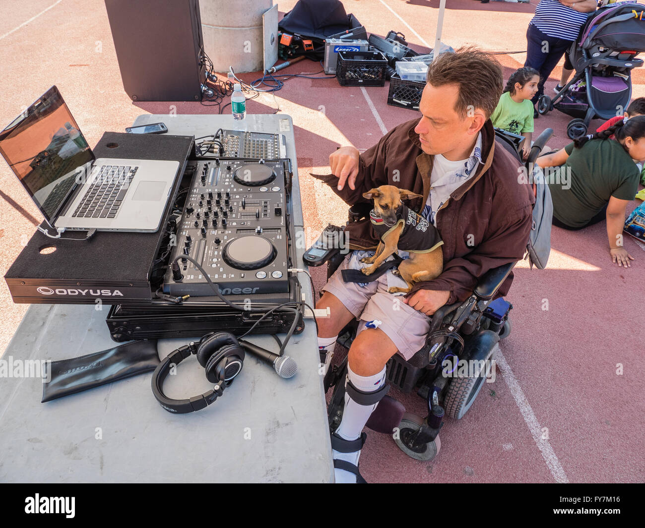 Un fauteuil roulant mobilité middle-aged man travaille son équipement sonore comme il travaille comme disc-jockey aux Jeux olympiques spéciaux. Banque D'Images