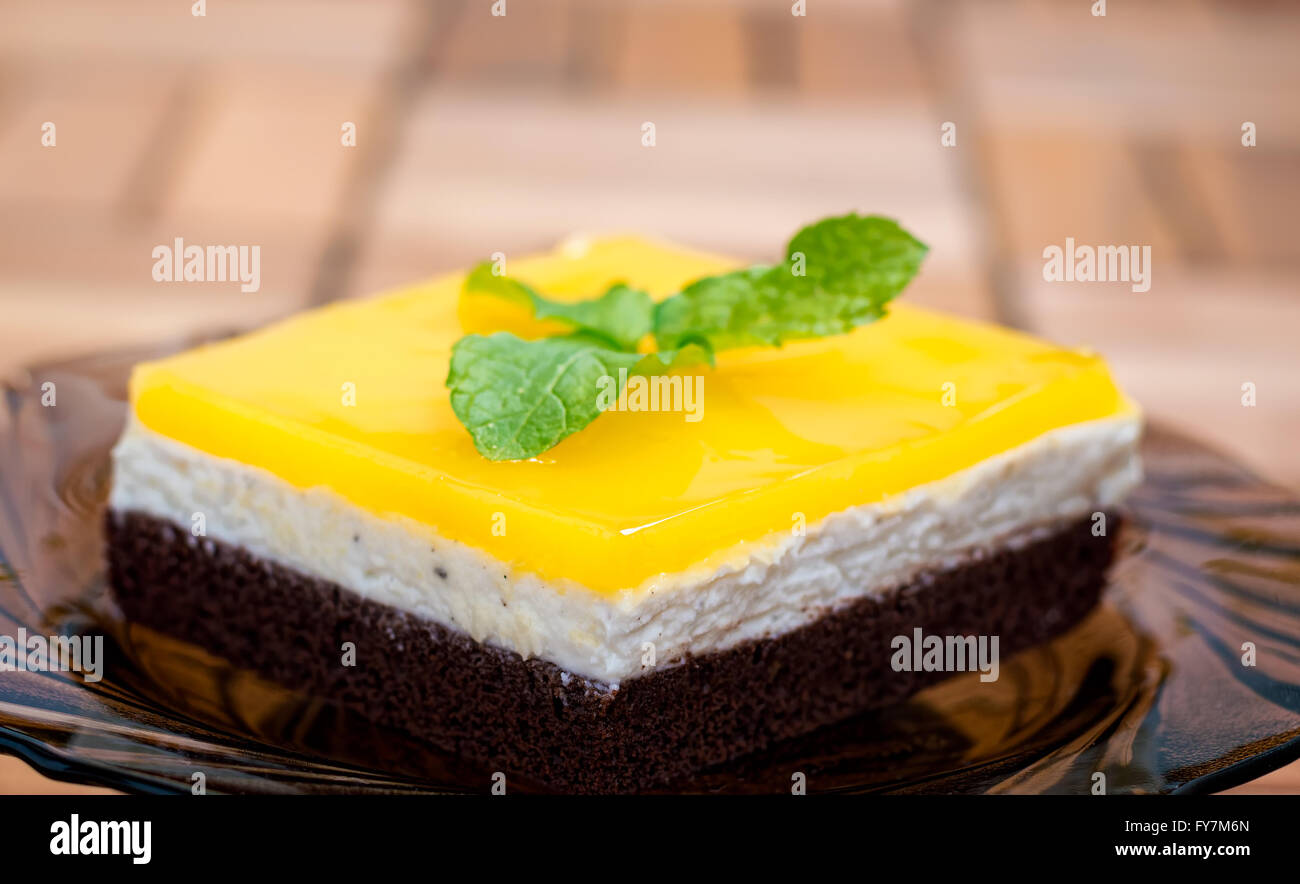 Vue latérale d'éponge chocolat, fromage à la crème et le jus d'orange jello topping gâteau décoré avec des feuilles de menthe. Banque D'Images