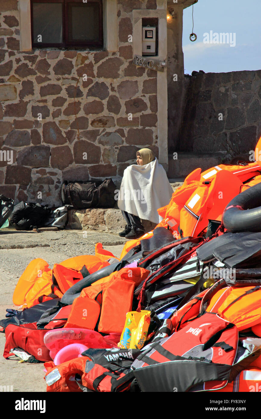 Un réfugié syrien s'est enveloppé dans une couverture de survie assise par des gilets de sauvetage jetés après son arrivée en bateau gonflable à Molyvos, sur l'île de Lesvos Banque D'Images