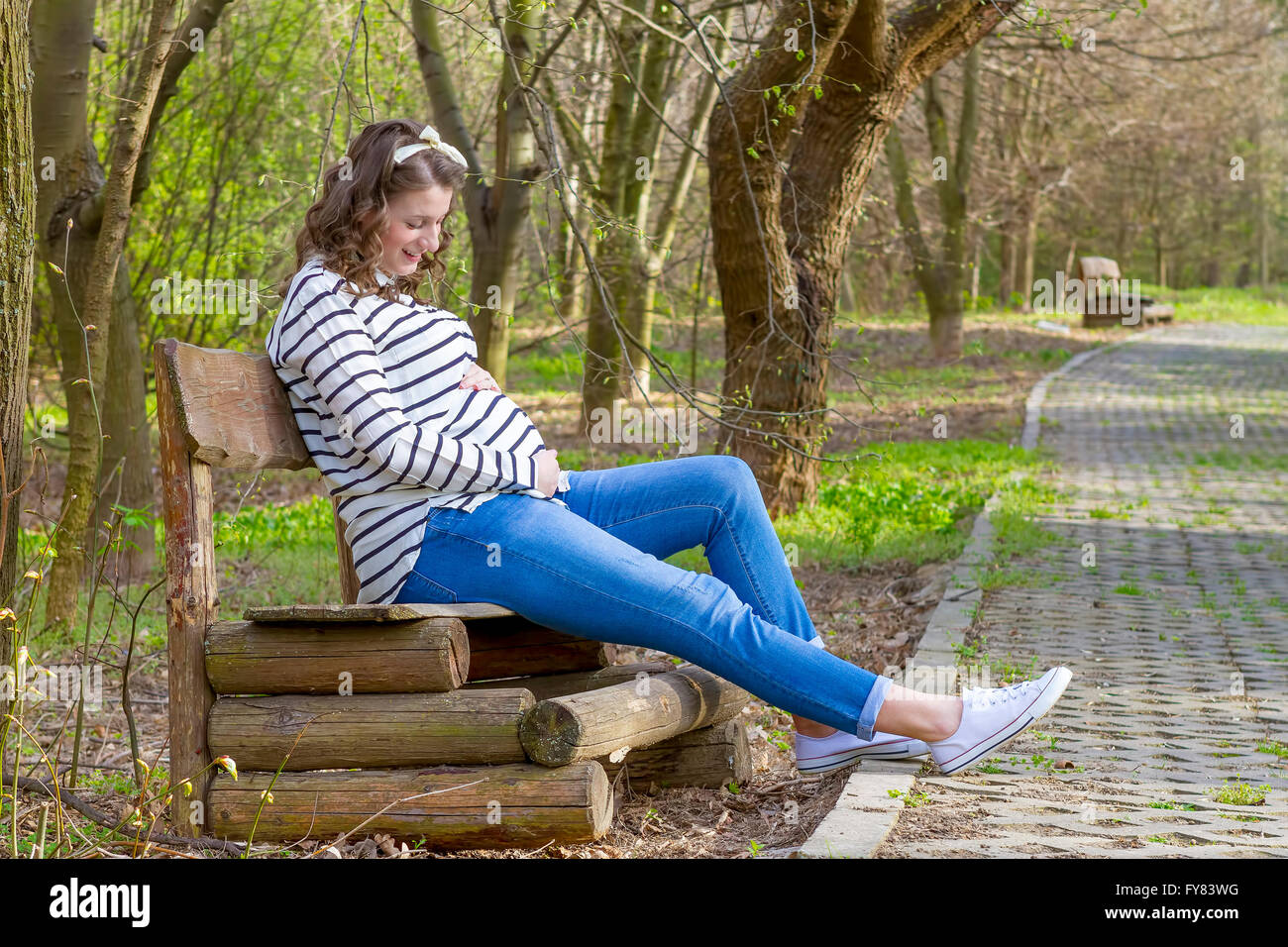 Beautiful pregnant woman smiling piscine dans le parc sur un banc. Banque D'Images