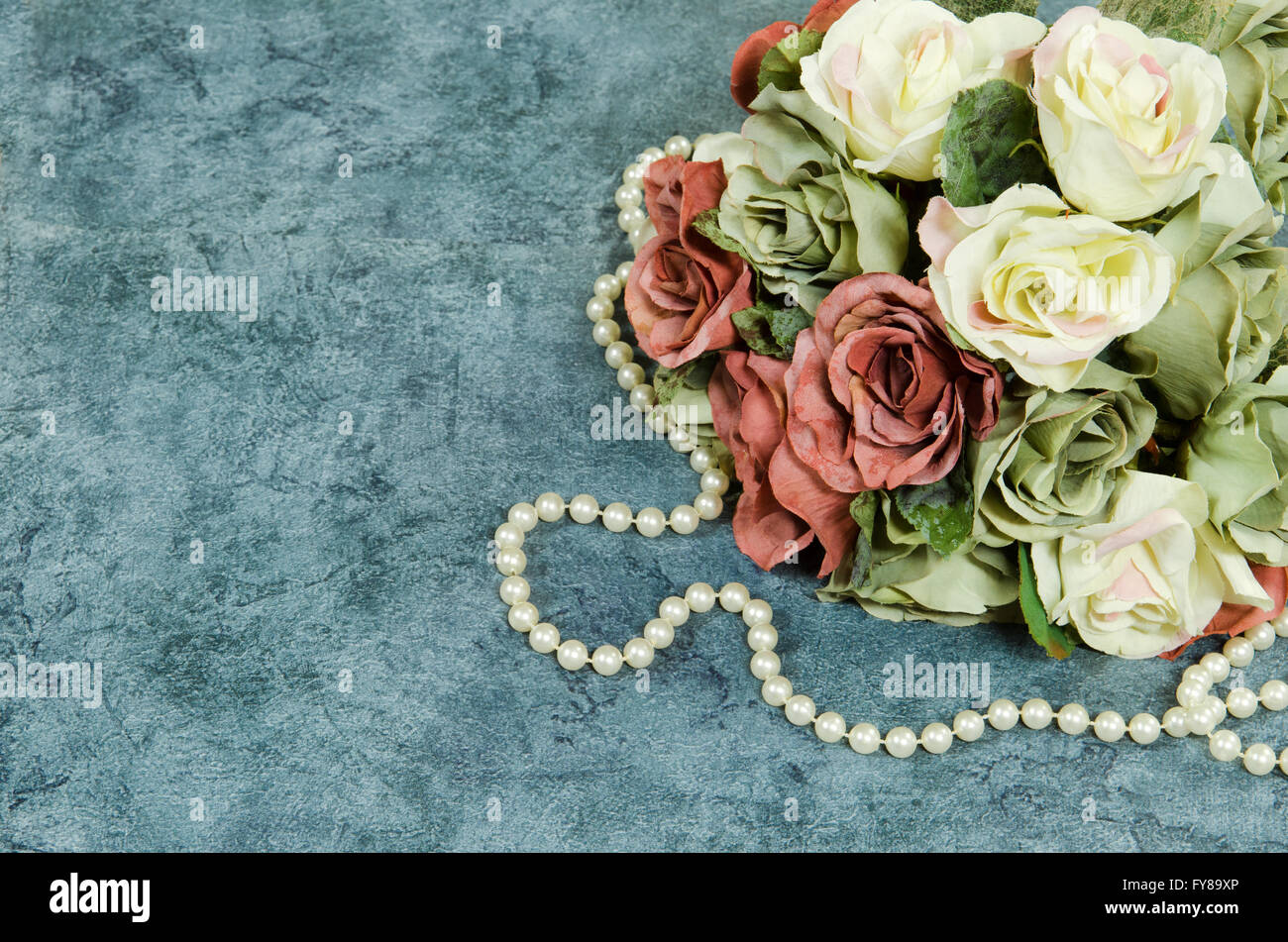 Bouquet de roses en soie avec un collier de perles sur un fond élégant Banque D'Images