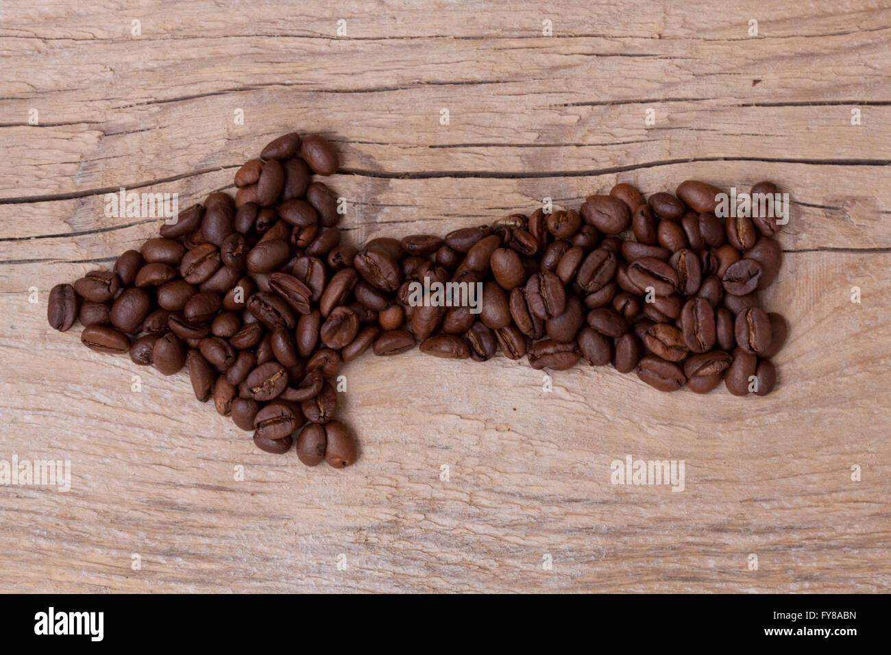 Les grains de café de flèche pointant vers une certaine direction, situé sur une vieille planche de bois, disposition horizontale Banque D'Images