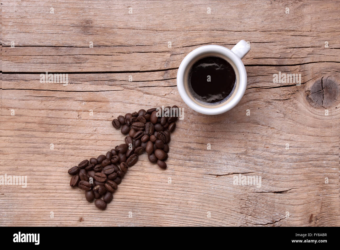 Les grains de café de flèche pointant sur une tasse de café, le tout sur une vieille planche de bois, modèle diagonal Banque D'Images