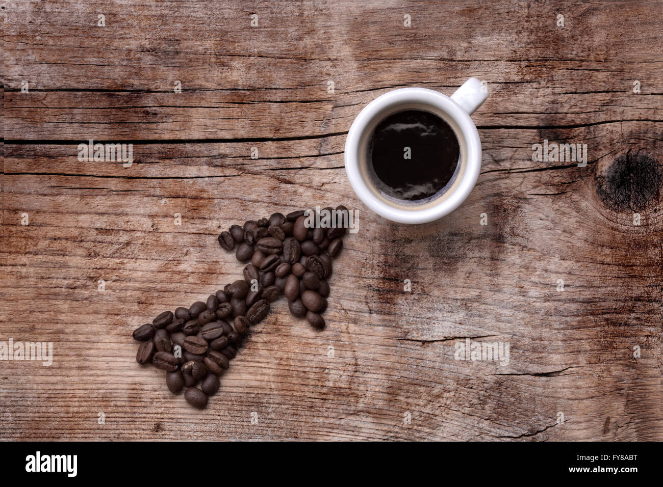 Les grains de café de flèche pointant sur une tasse de café, le tout sur une vieille planche de bois, modèle diagonal Banque D'Images
