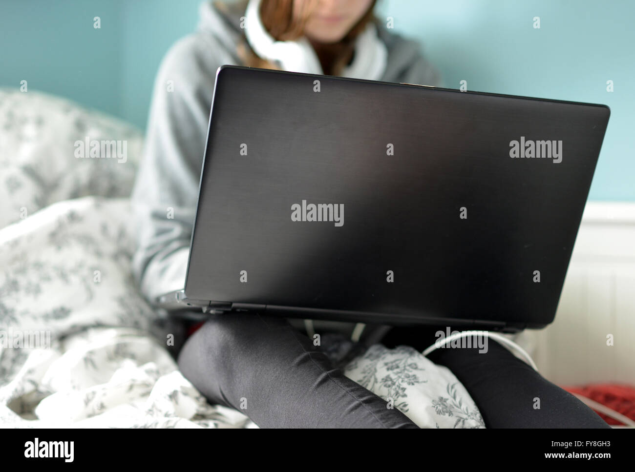 Teen girl sur un ordinateur portable dans sa chambre à coucher Banque D'Images