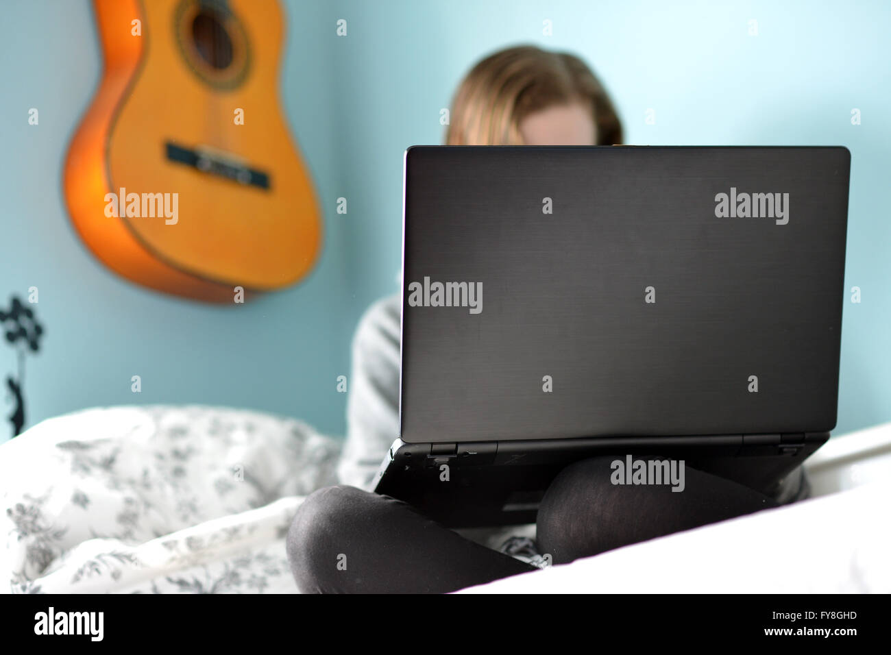Teen girl sur un ordinateur portable dans sa chambre à coucher Banque D'Images