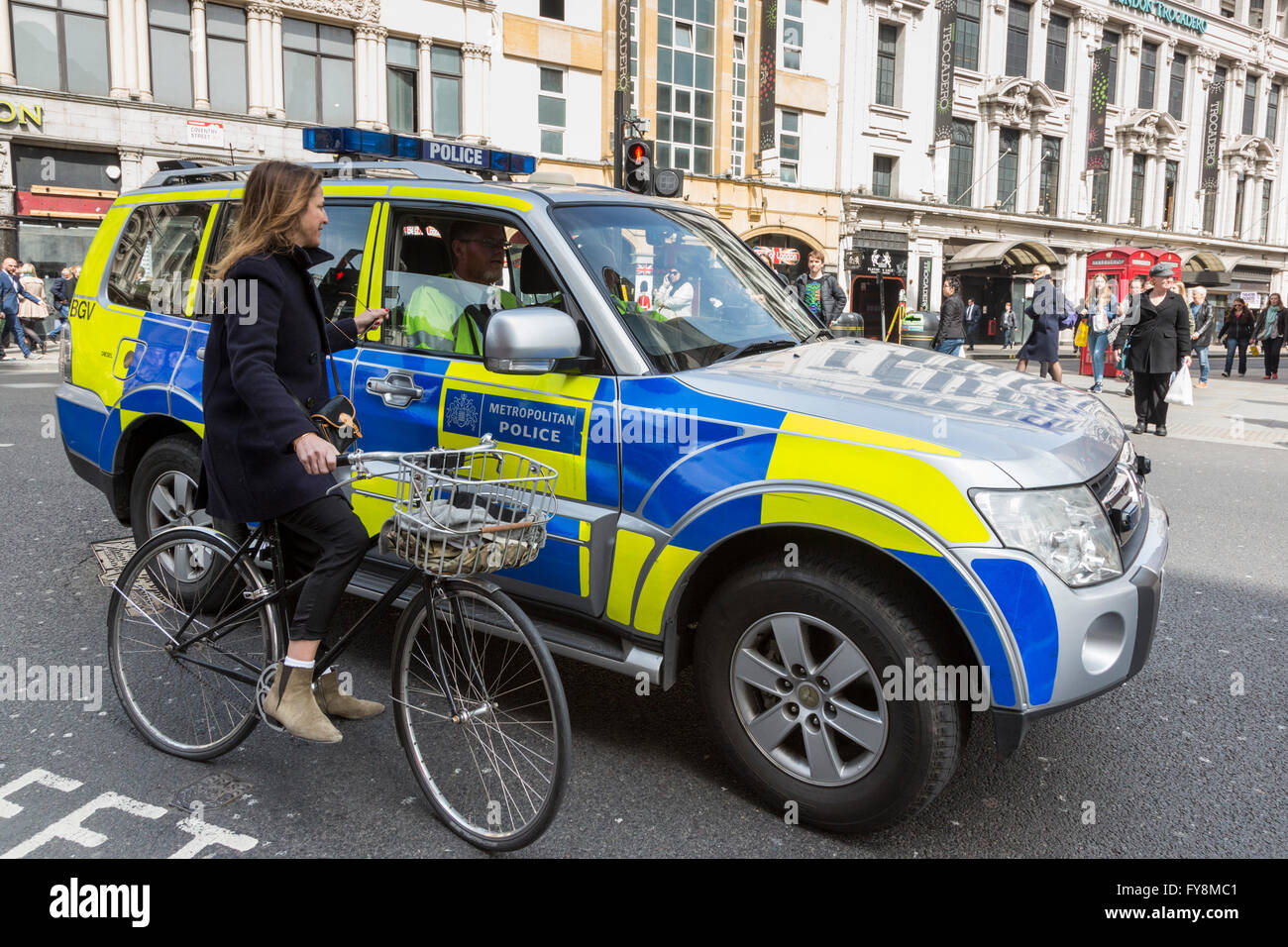 Officier de police dans une voiture de police parlant à un cycliste féminin, Londres, Angleterre, Royaume-Uni Banque D'Images