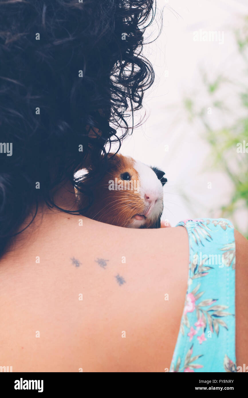 Vue arrière de jeune femme avec cochon sur son épaule Banque D'Images