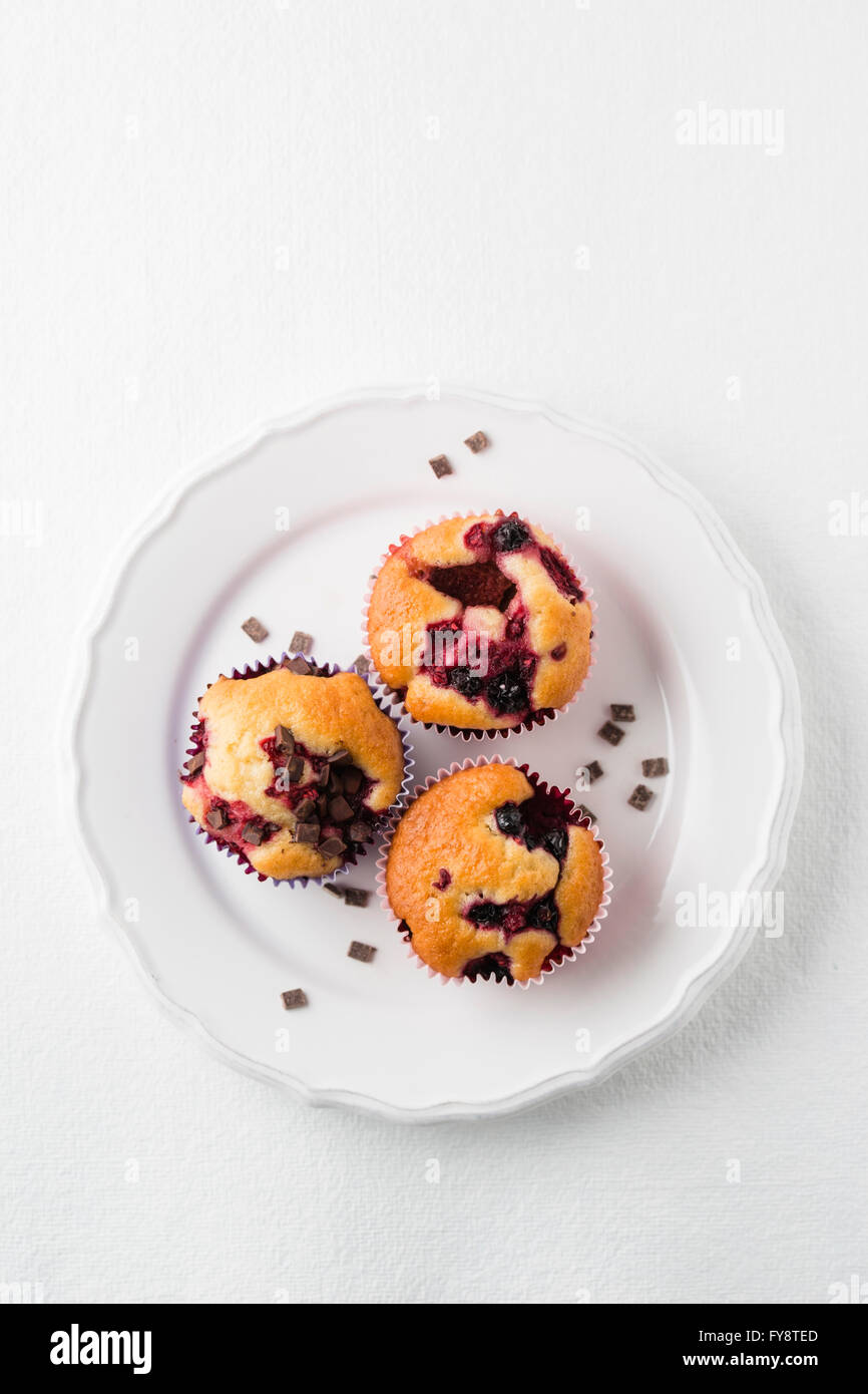 Les muffins aux pépites de chocolat, bleuets et framboises sur la plaque Banque D'Images