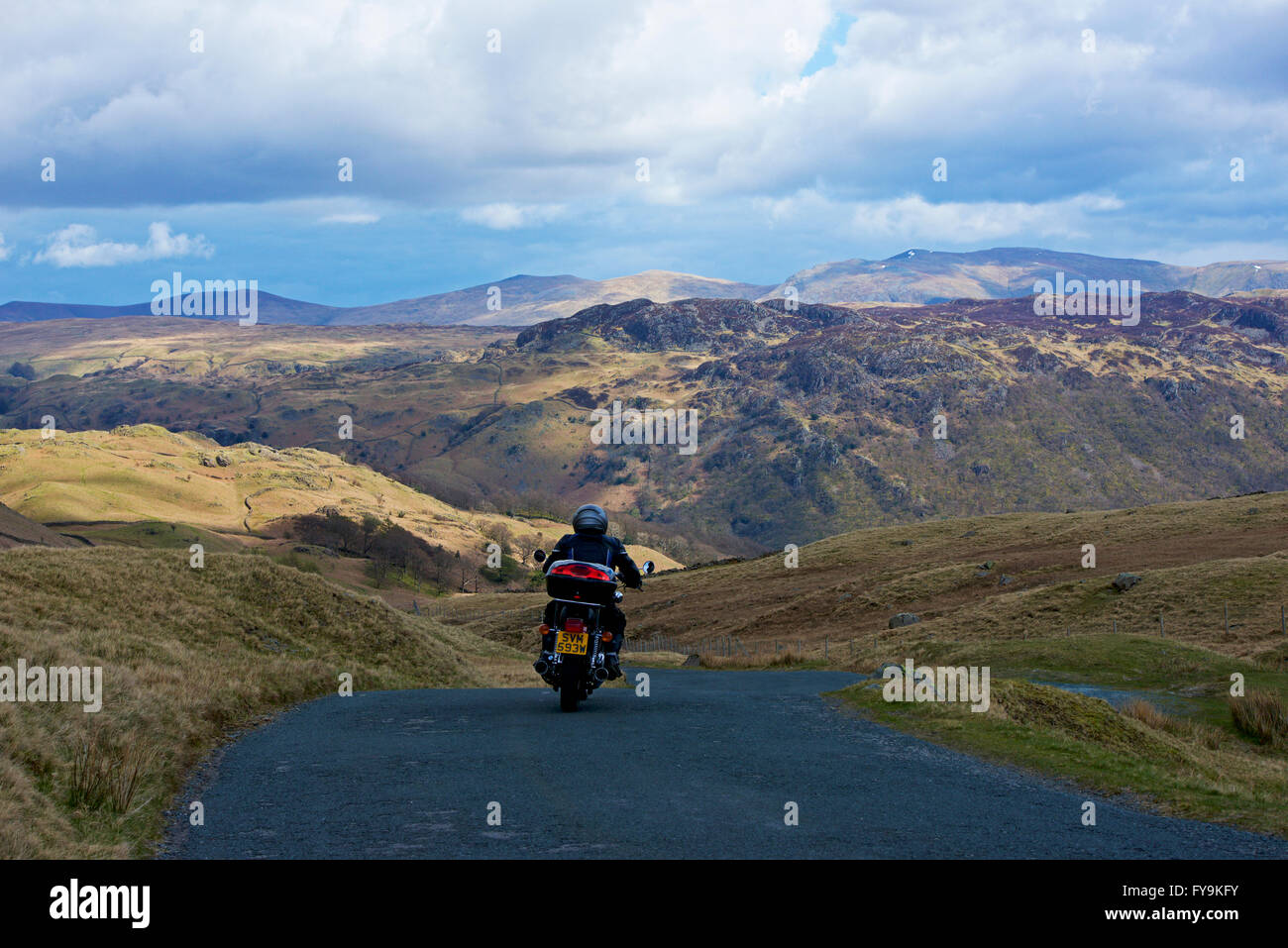 Homme à moto descendant le col Honister (B5289), parc national du Lake District, Cumbria, Angleterre Banque D'Images