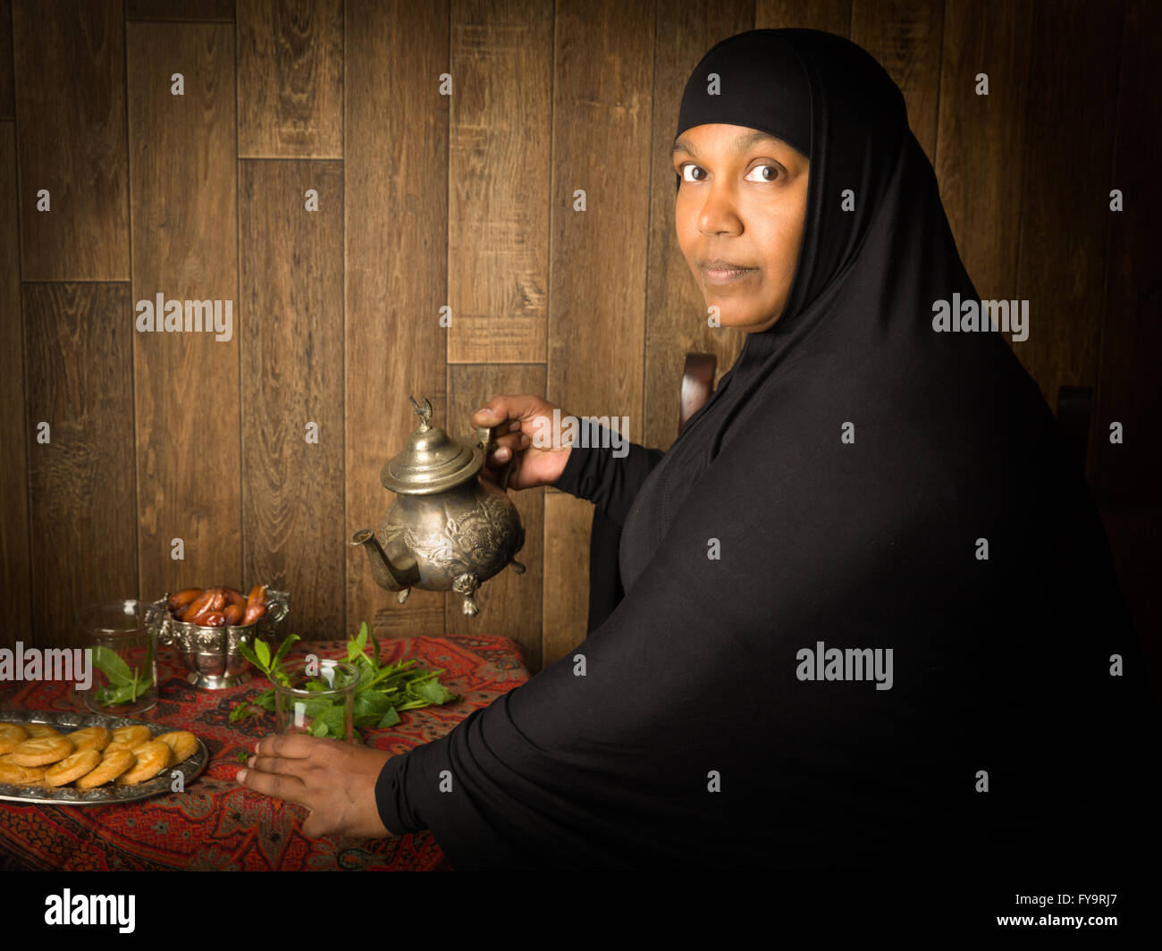 Smiling muslim woman pouring thé à la menthe la manière traditionnelle Banque D'Images