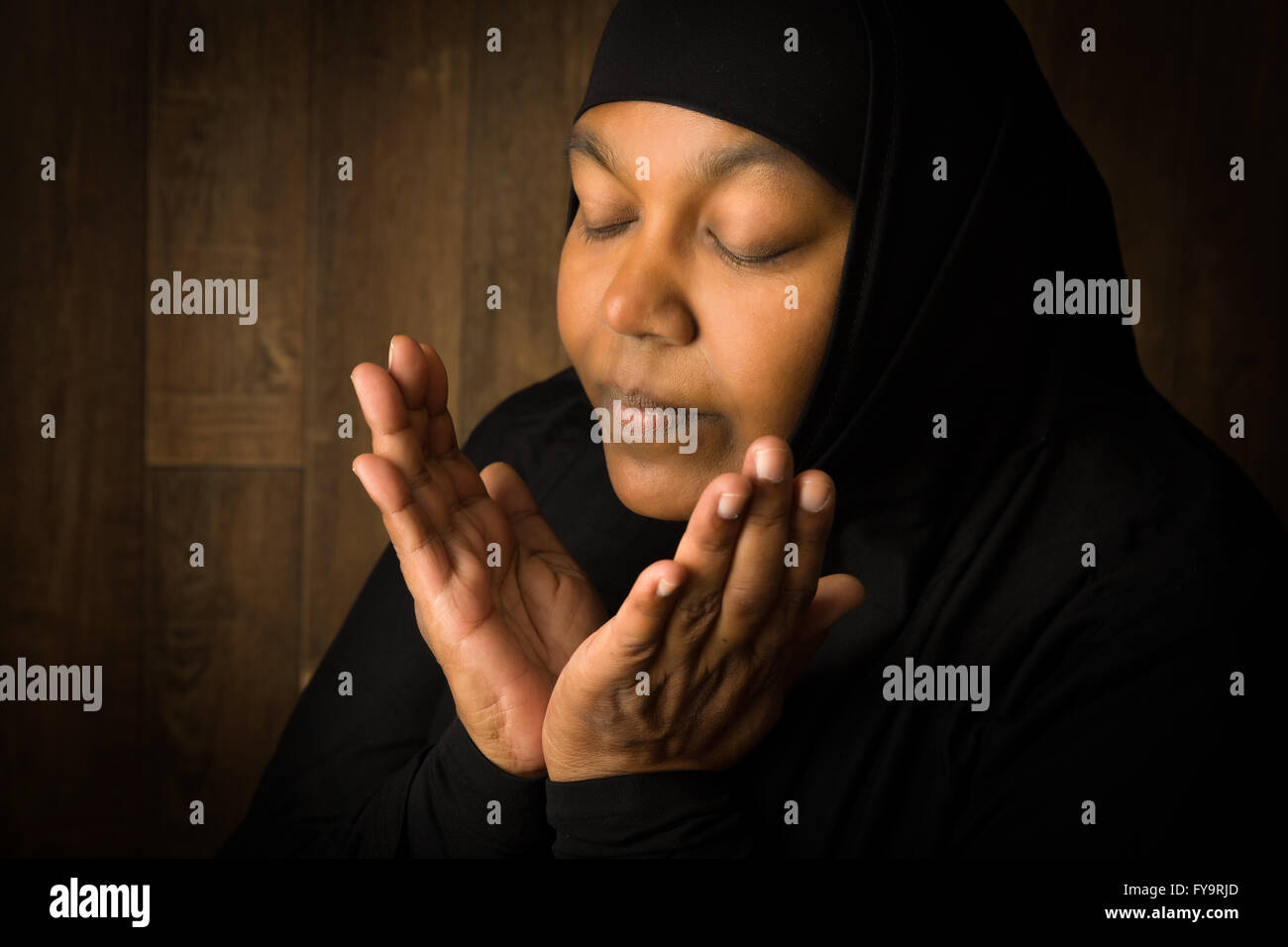 Femme musulmane africaine weiring un voile noir dans la prière Banque D'Images