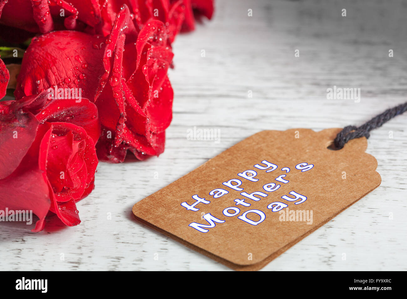 Happy Mother's Day text avec des roses rouges sur la table rustique en bois blanc Banque D'Images