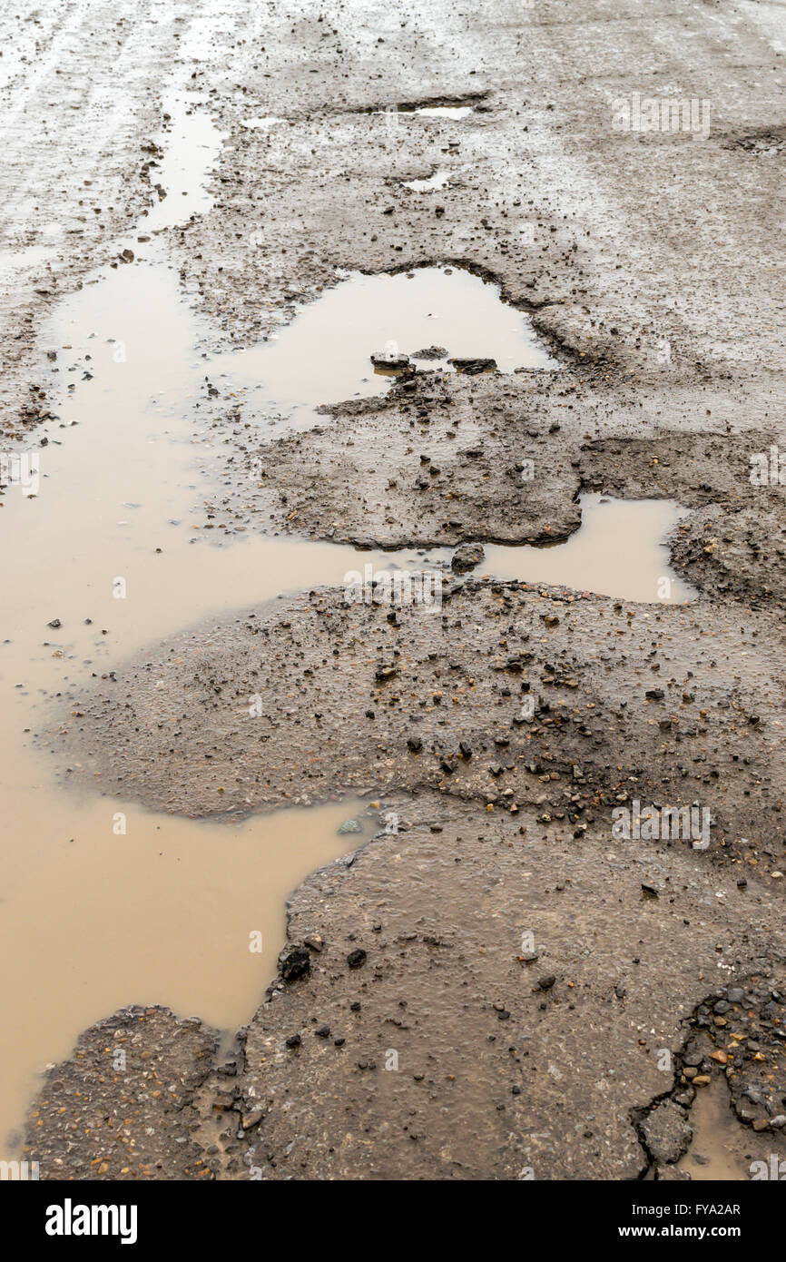 De grandes fosses dans un chemin goudronné rempli de pluie boueuse. Copie espace salon pour la réparation des routes construction conçoit et con Banque D'Images