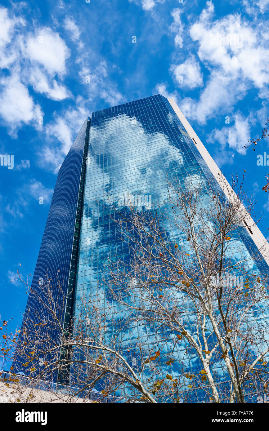 Un low angle shot avec un grand bâtiment en verre réfléchissant à l'arrière-plan avec ciel bleu. Banque D'Images