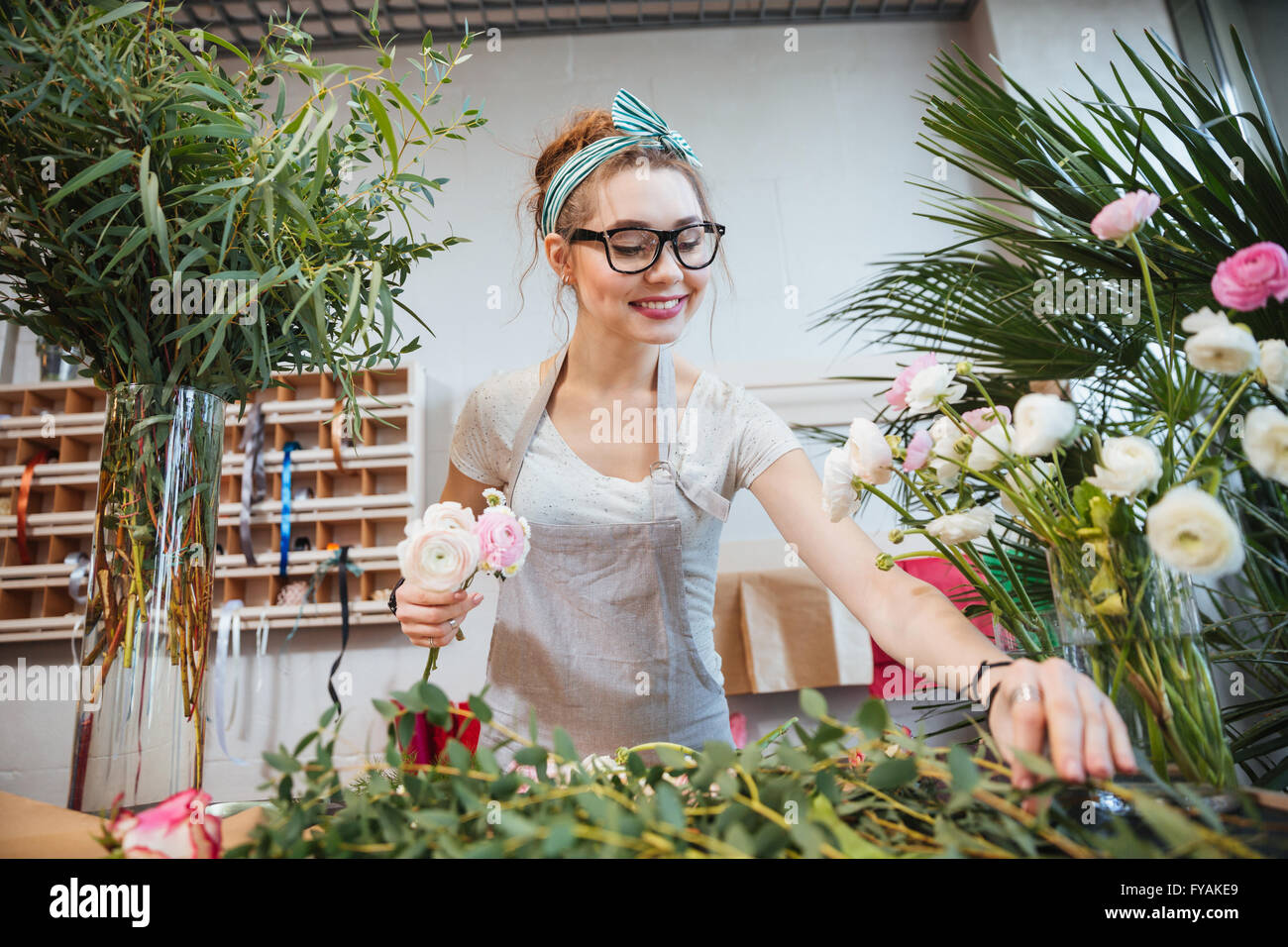 Heureux jolie jeune femme faire fleuriste bouquet in flower shop Banque D'Images