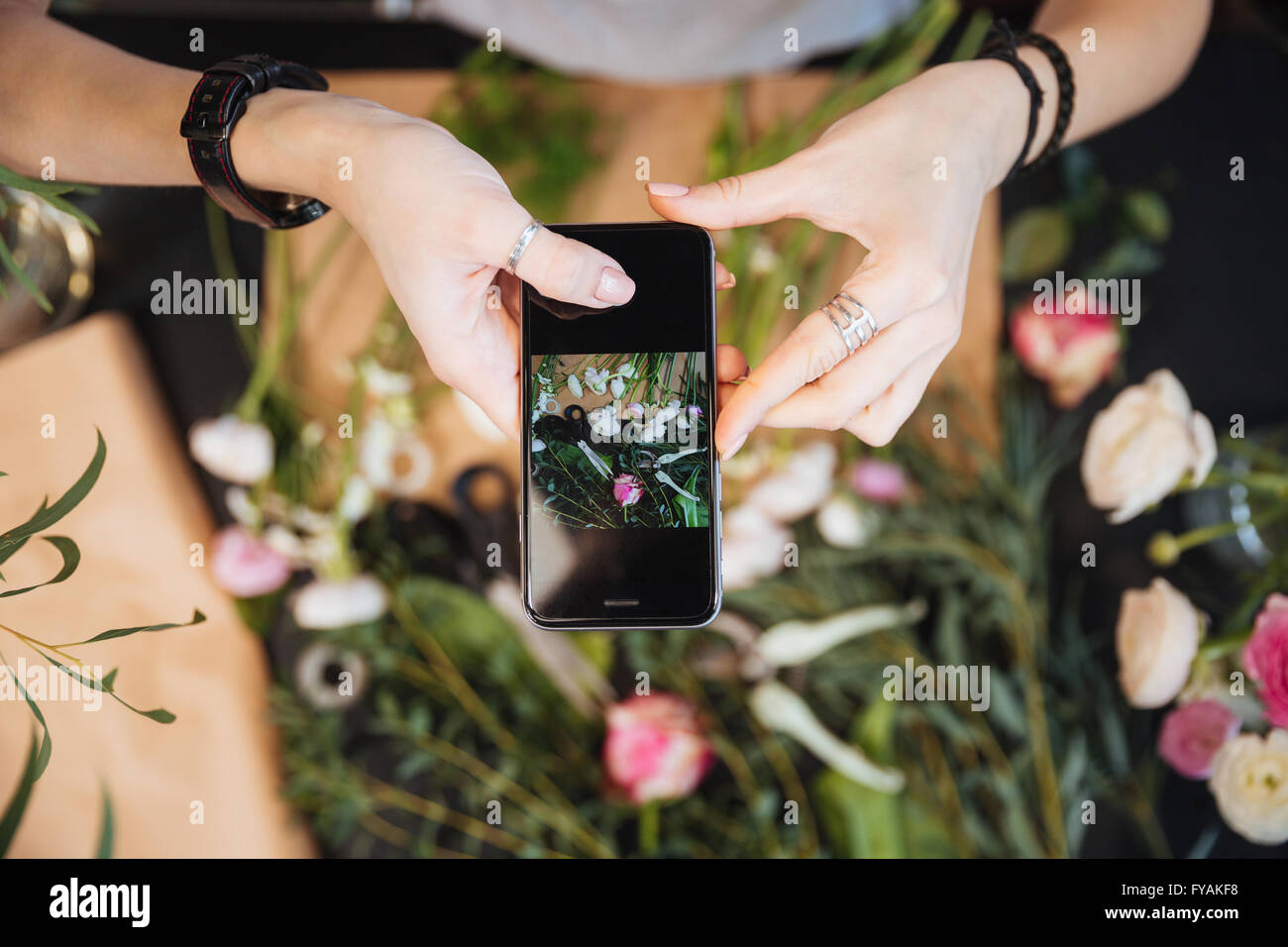 Vue de dessus de mains de fleuriste femme prendre des photos de fleurs avec un téléphone mobile Banque D'Images