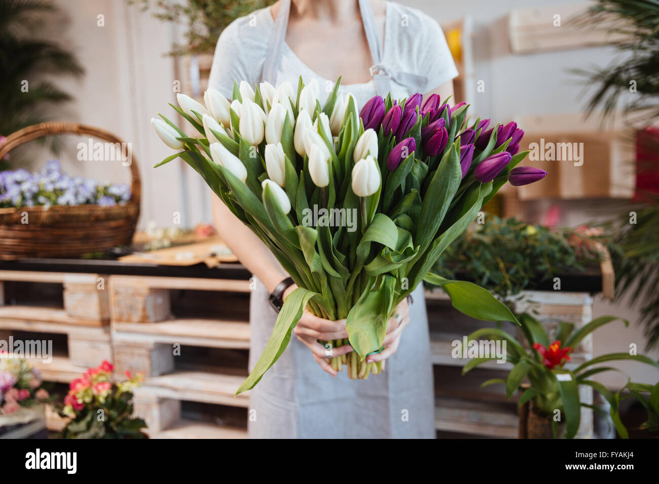 Gros plan du jeune femme debout et tenant fleuriste bouquet de tulipes dans le magasin de fleurs Banque D'Images