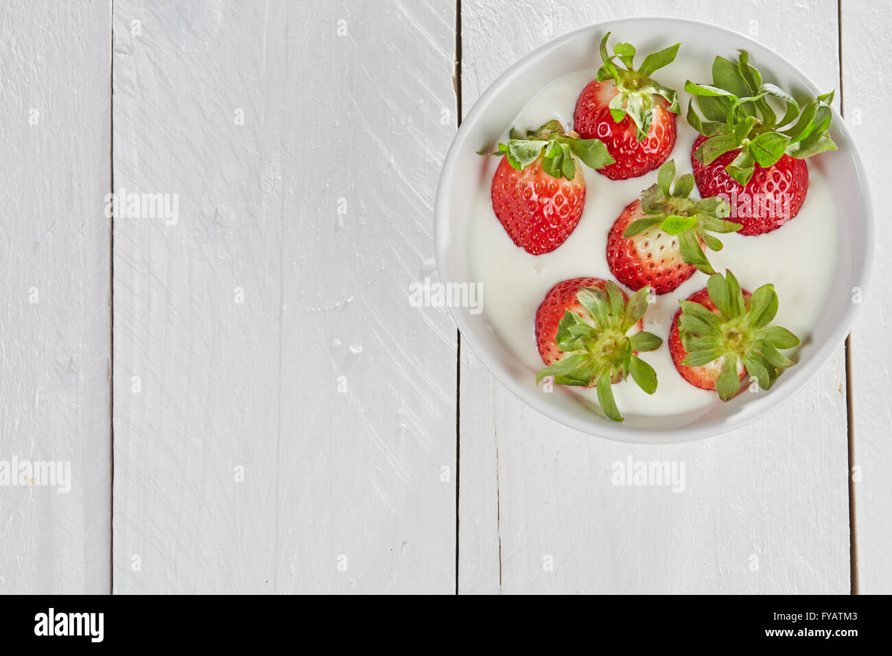 Dans strasberries avec bol Smoothie yaourt blanc sur une table en bois blanc Banque D'Images
