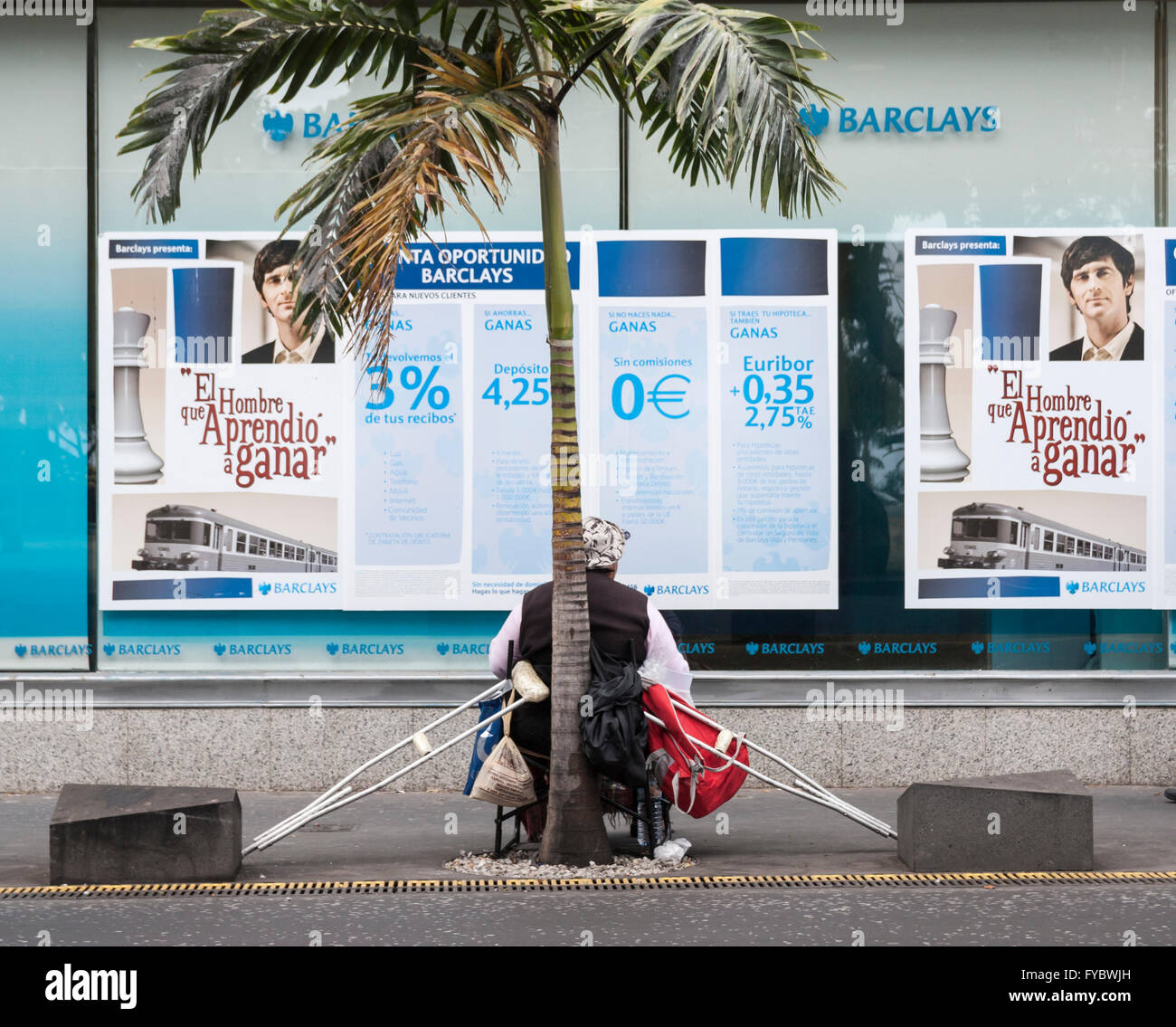 Homme avec des béquilles mendier à l'extérieur de la banque Barclays en Espagne Banque D'Images