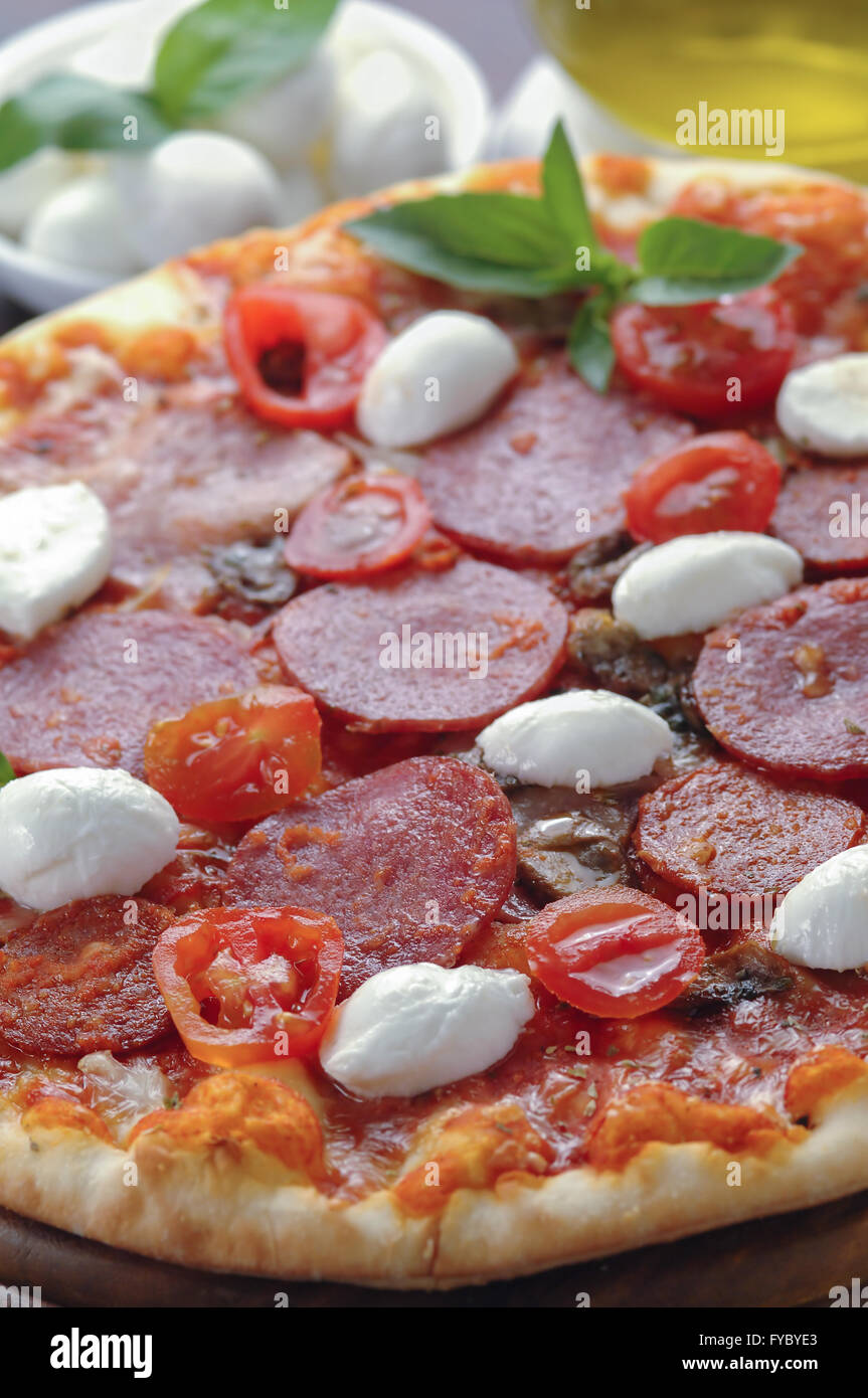 Salami et la tomate fraîche pizza avec feuilles de basilic frais Banque D'Images