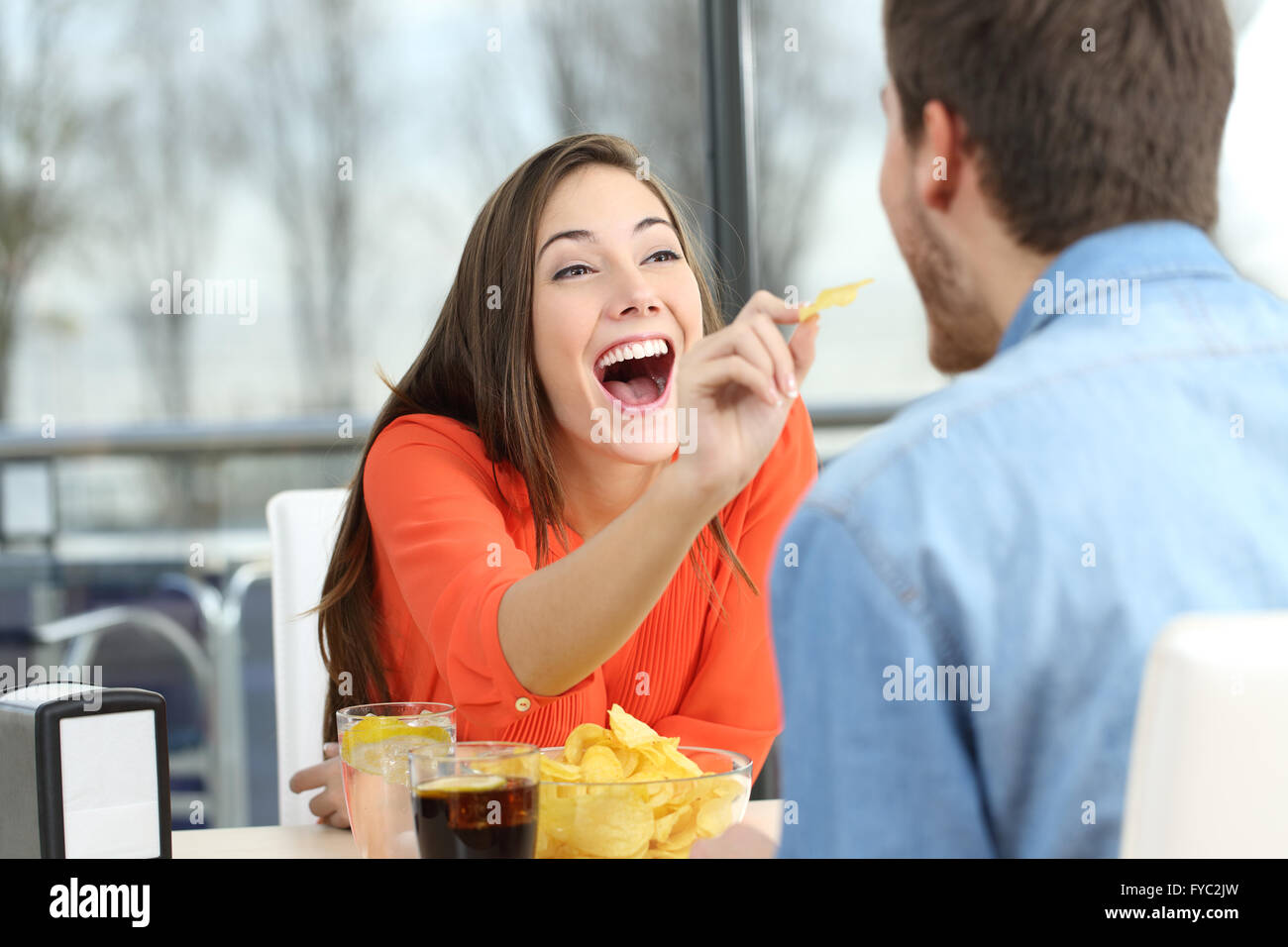 Playful couple puce manger des pommes de terre et de plaisanter à l'autre dans une date dans un café Banque D'Images