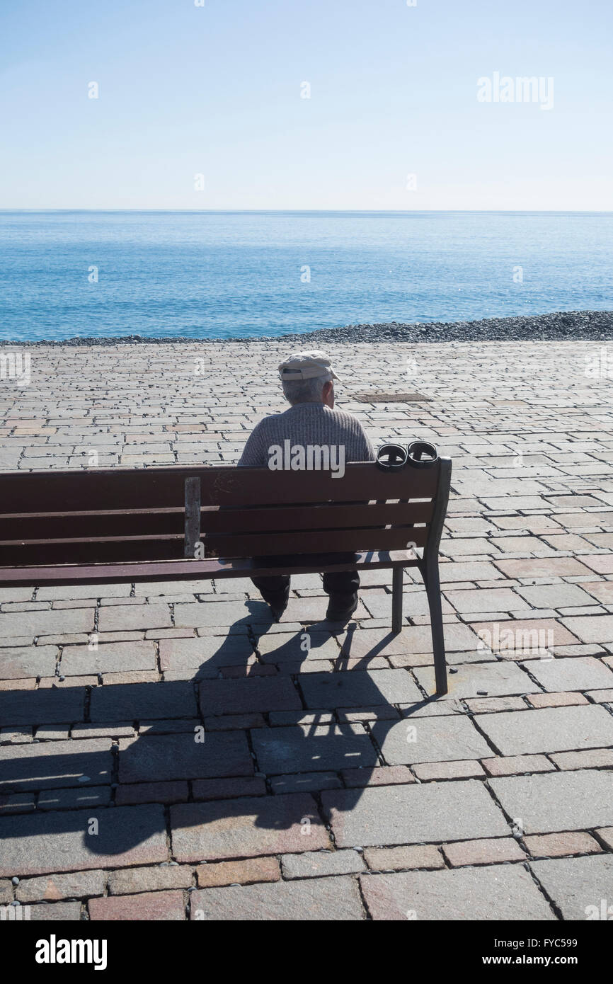 Vieil homme avec des béquilles assis sur son fauteuil avec vue sur la mer. Espagne Banque D'Images