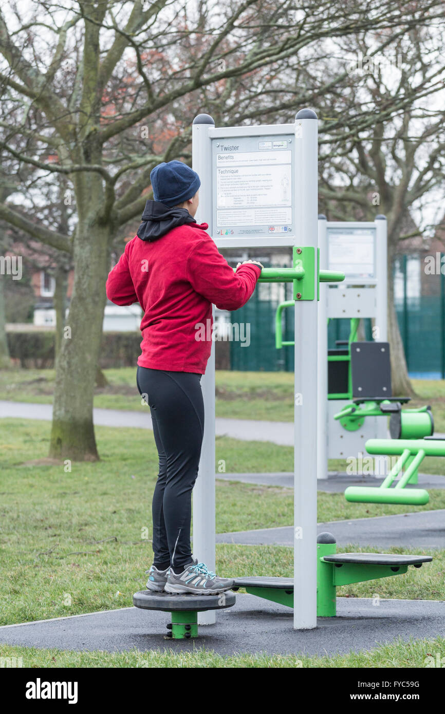 Woman using exercise machine en parc public. L'Angleterre. UK Banque D'Images