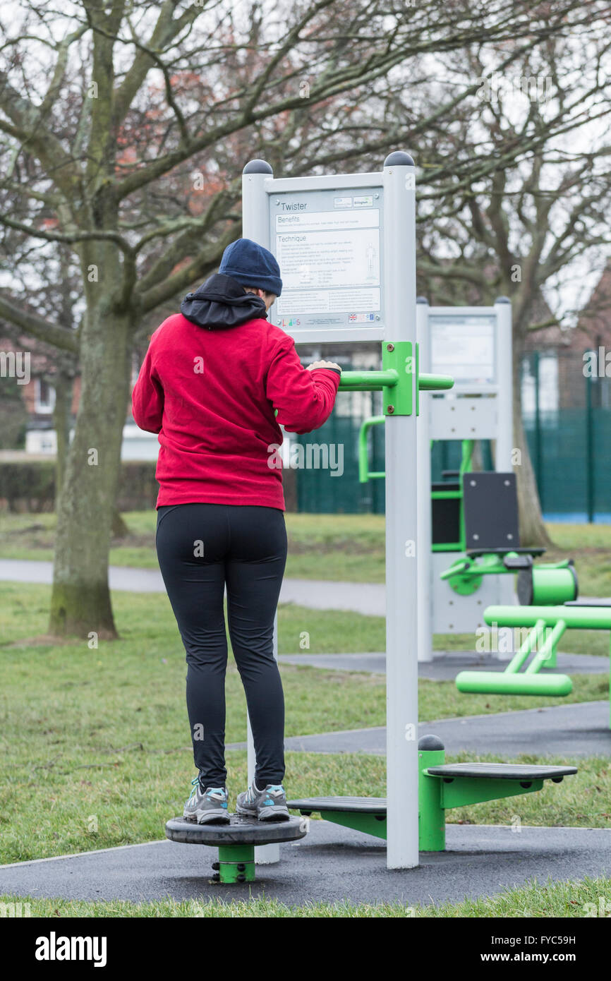 Femme à l'aide de machine d'exercice de la hanche twister en parc public. L'Angleterre. UK Banque D'Images