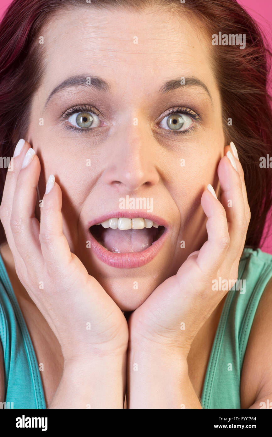 Les mains sur le visage femme surprise Banque D'Images