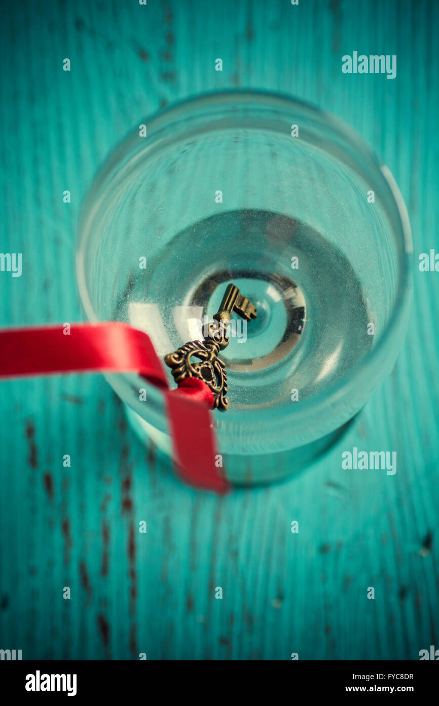 Ancienne clé avec un ruban rouge à l'intérieur d'un verre Banque D'Images