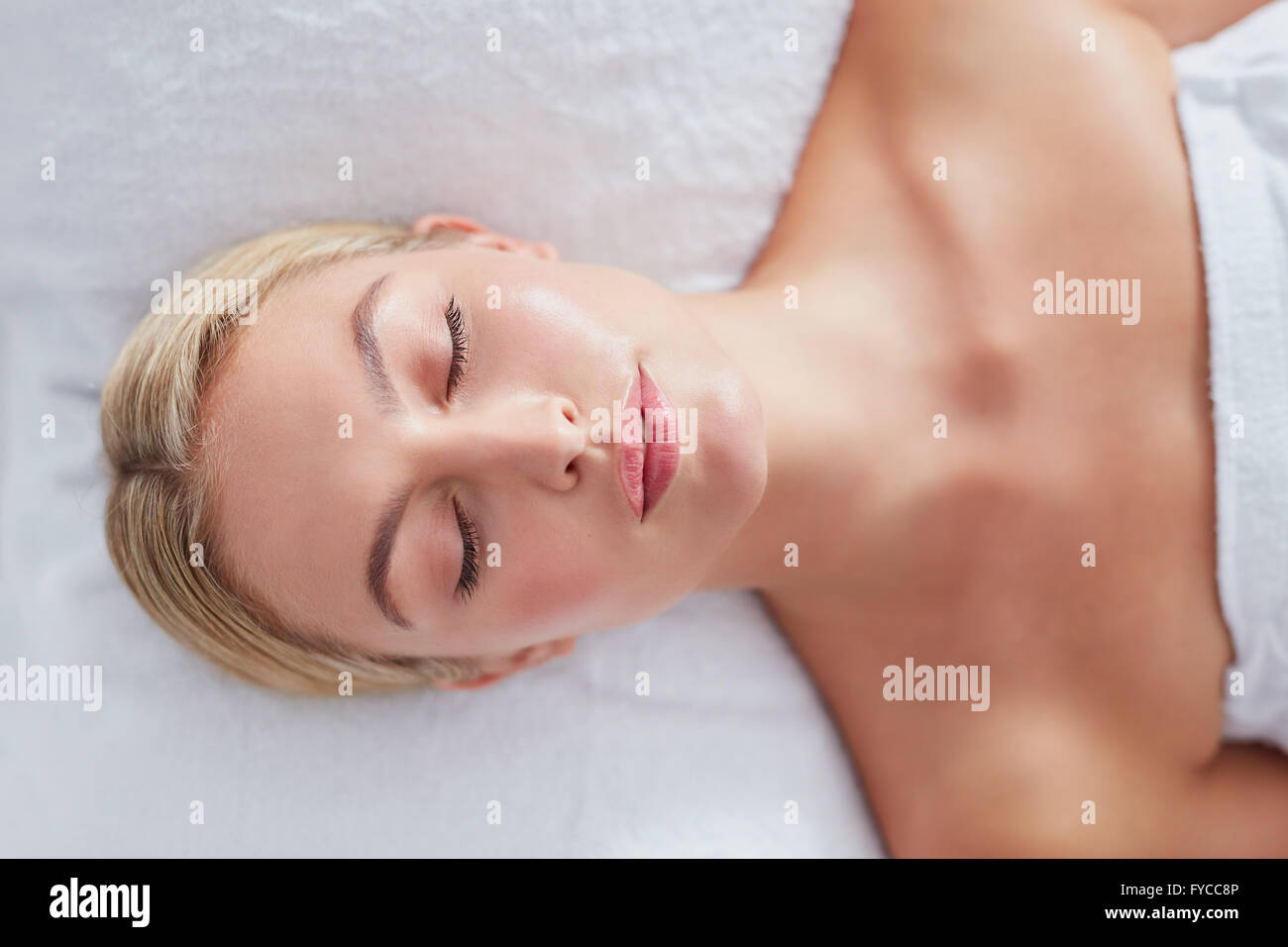 Vue du dessus de l'attractive young woman relaxing with her les yeux fermés sur une table de massage. Médecine centres de woman. Banque D'Images