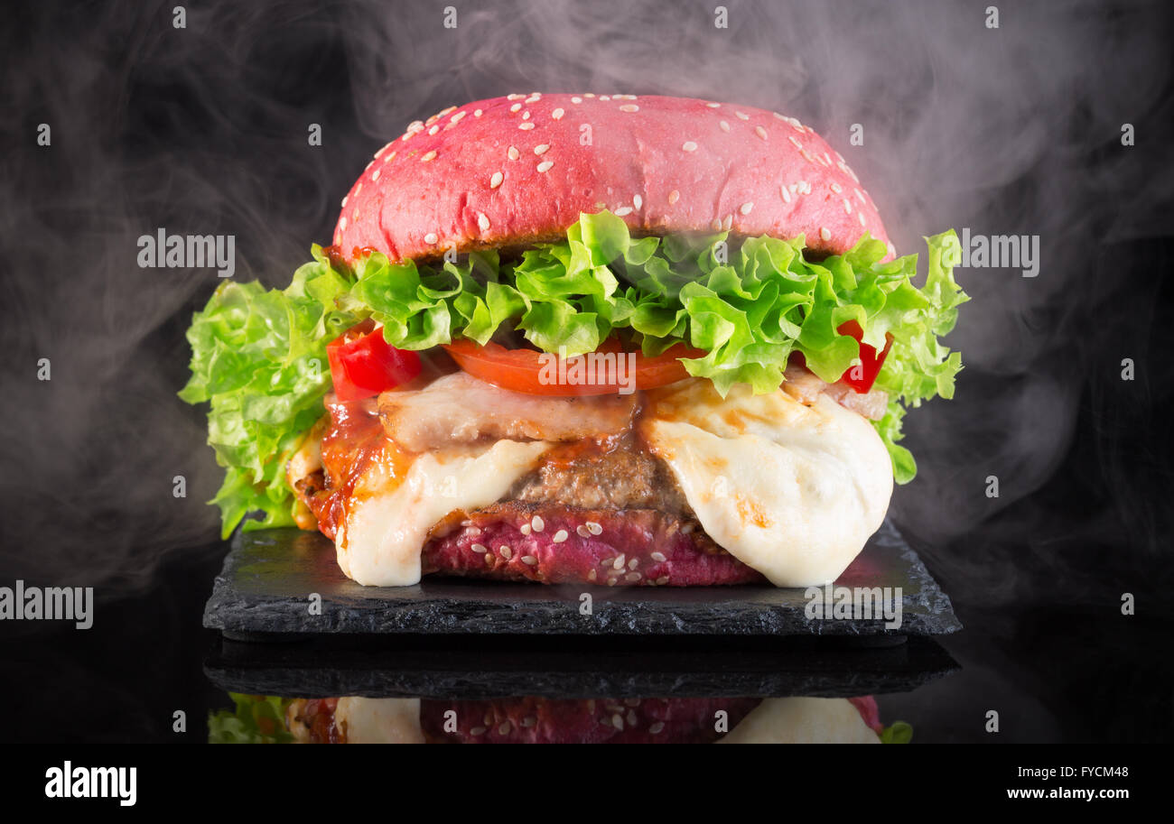 Big Red hamburger avec de la fumée sur un tableau d'ardoise. Banque D'Images