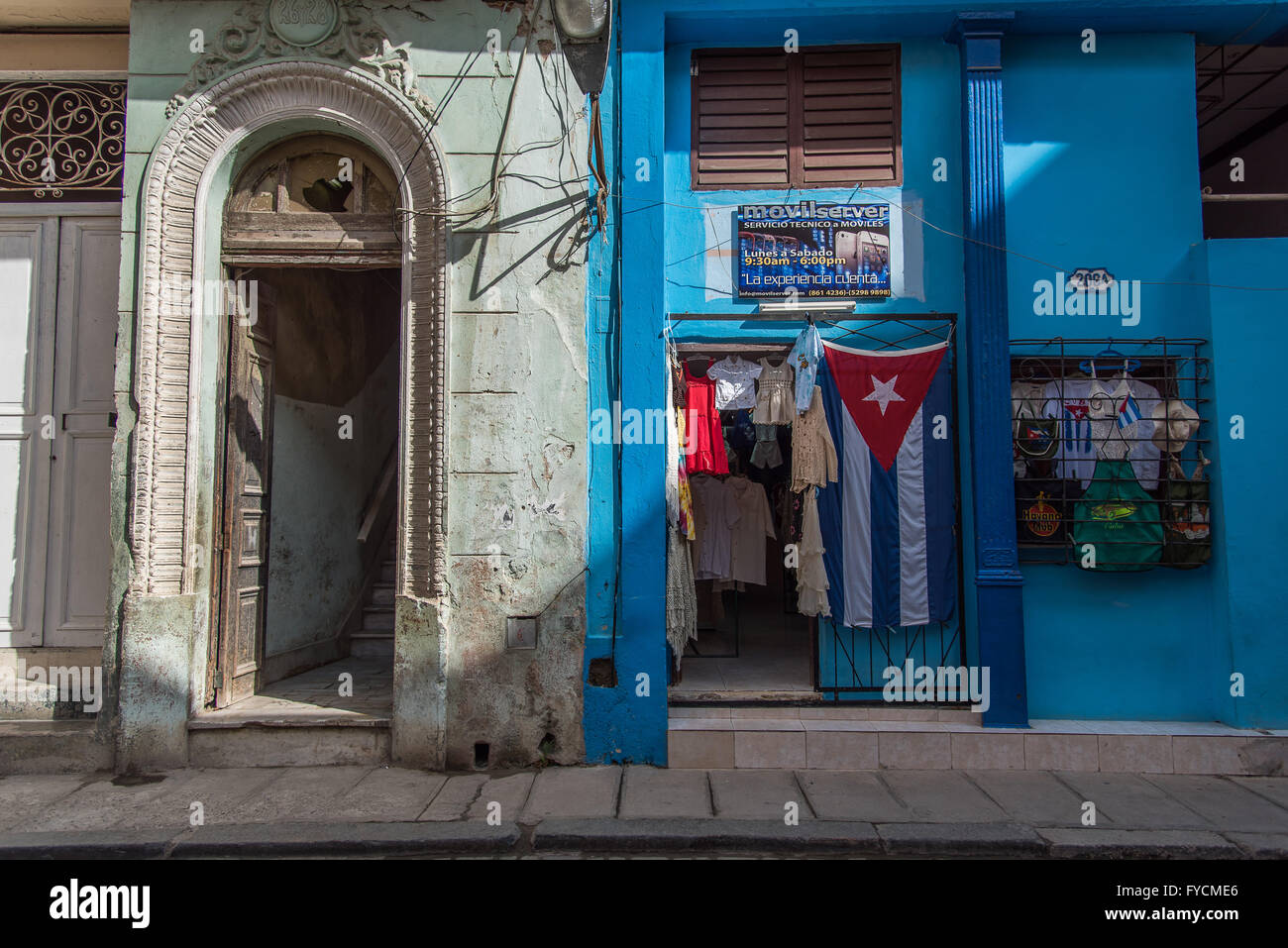 Une boutique typique de l'avant dans la vieille Havane à vendre des tissus, des vêtements et des sacs. Un drapeaux cubain se bloque à l'extérieur, féliciter le mur bleu Banque D'Images