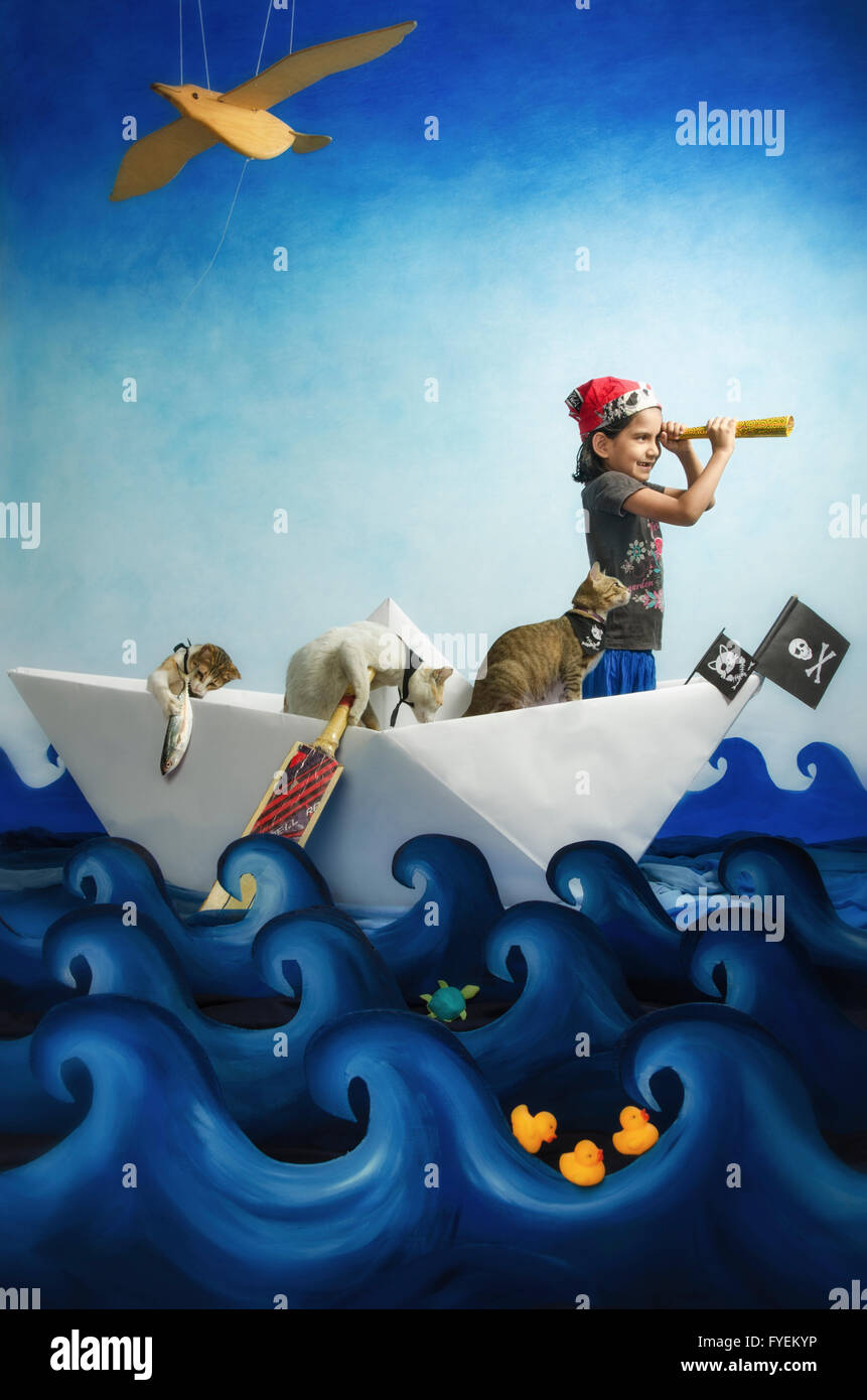 Une petite fille jouant avec les pirates plongé son animal de chats, d'un déplacement sur un océan imaginaire dans un bateau en papier pour ne jamais, jamais la terre. Banque D'Images