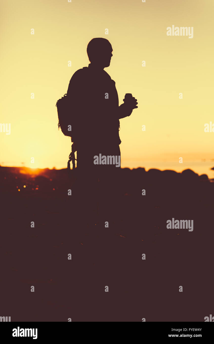 Silhouette de la personne tenant dans la main un verre dans une bouteille. Banque D'Images