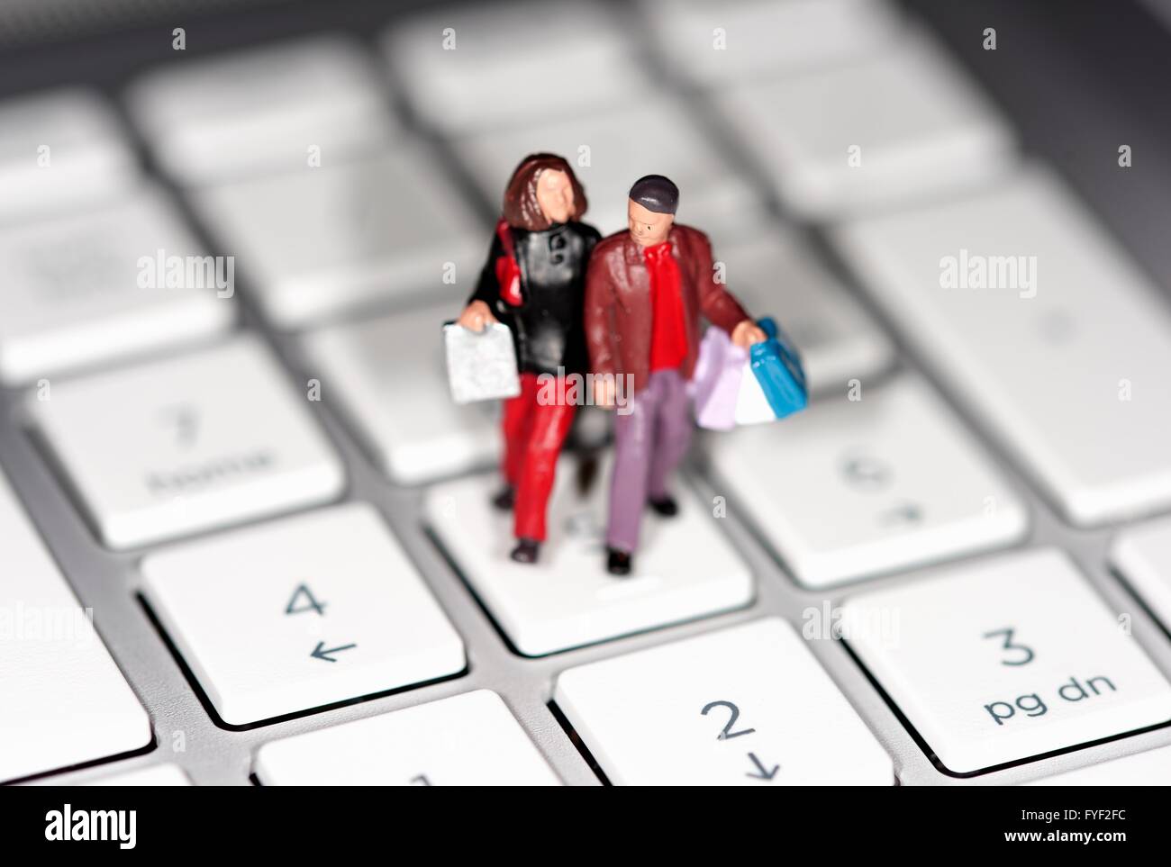 Une figurine miniature couple carrying shopping bags sur un clavier d'ordinateur portable Banque D'Images