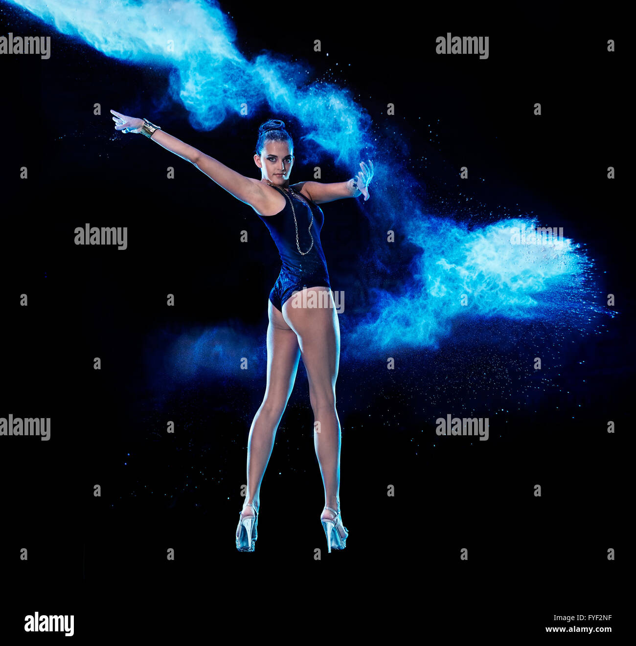 Jeune femme sautant en bleu nuage de poudre sur fond noir Banque D'Images