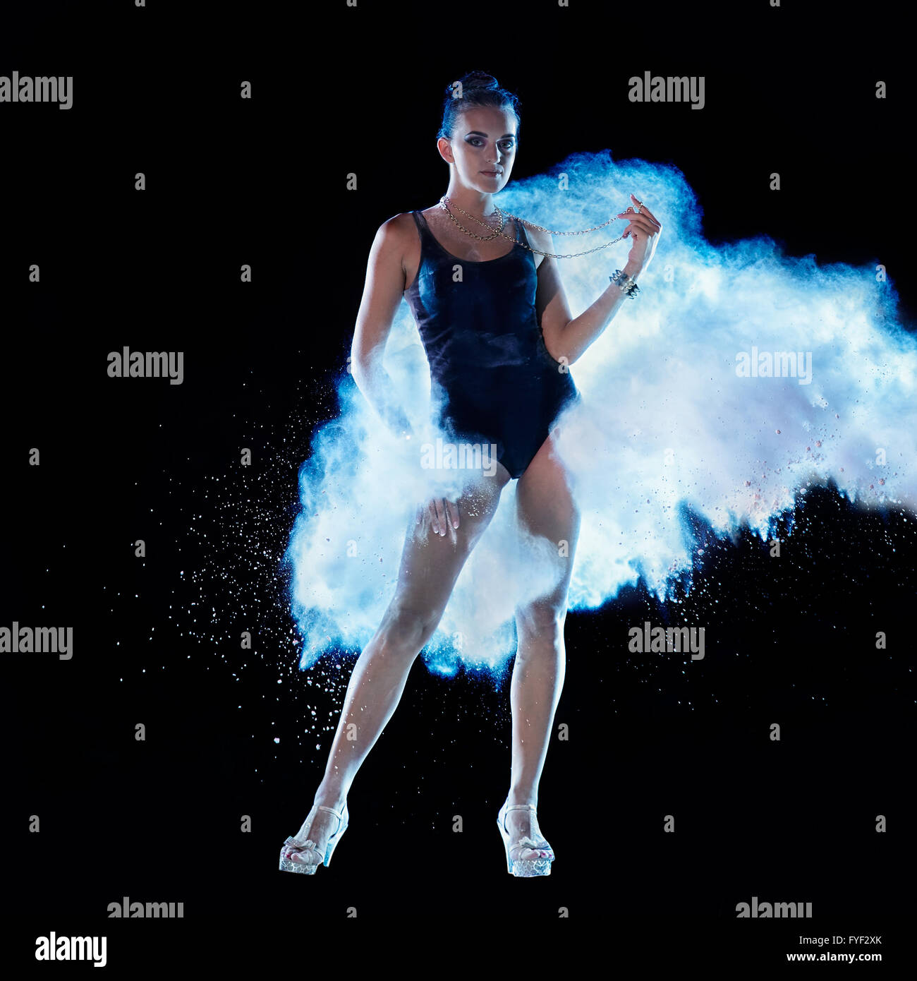 Jeune femme sautant en bleu nuage de poudre sur fond noir Banque D'Images