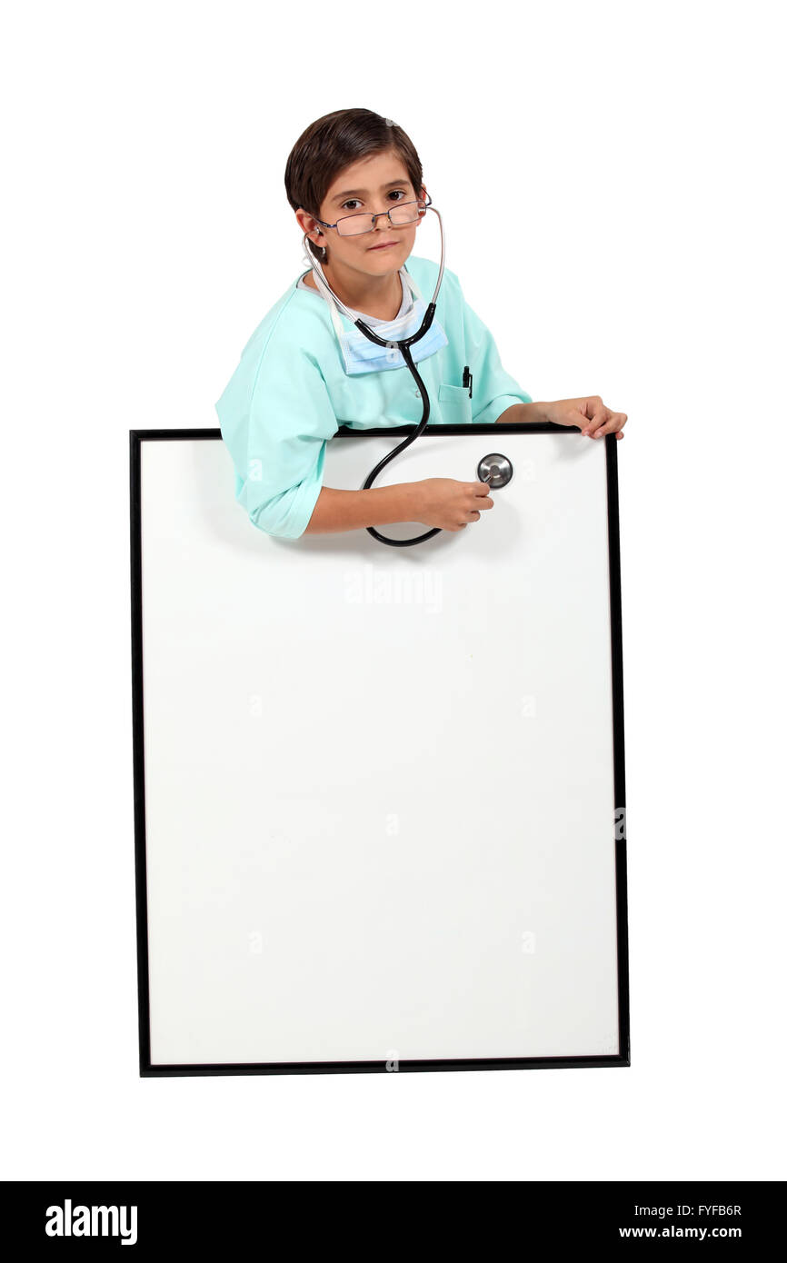 Petit garçon habillé comme un médecin à l'aide d'un stéthoscope sur un tableau blanc Banque D'Images