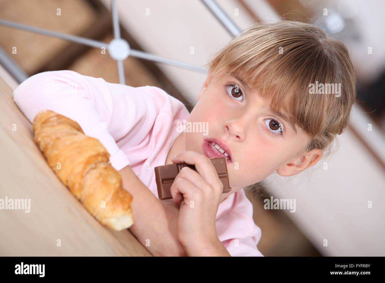 Jeune fille avec un croissant et barre de chocolat Banque D'Images